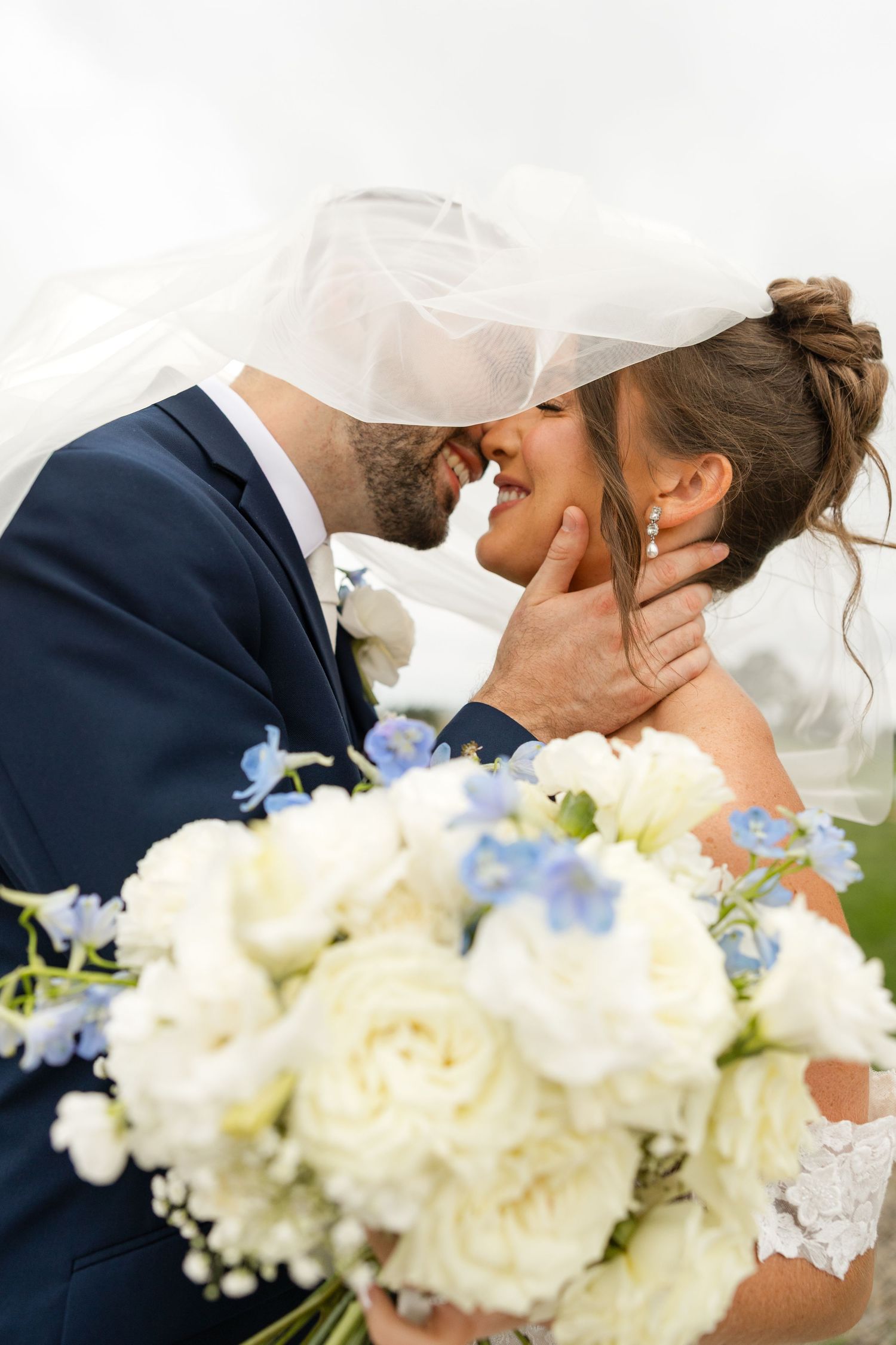 A romantic wedding moment captured with white and blue floral bouquet in the foreground.