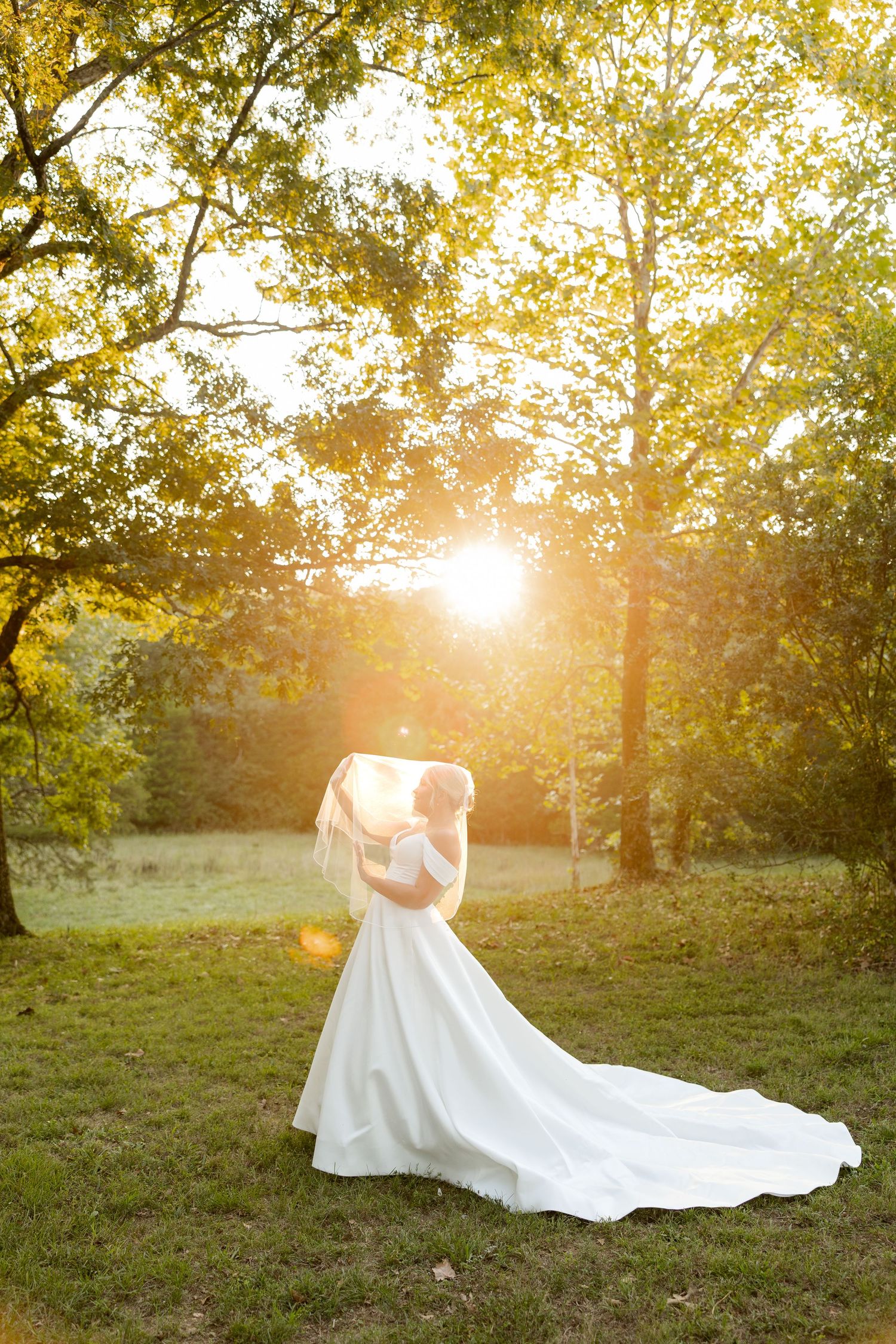 An elegant wedding dress silhouette captured against golden sunlight filtering through autumn trees.