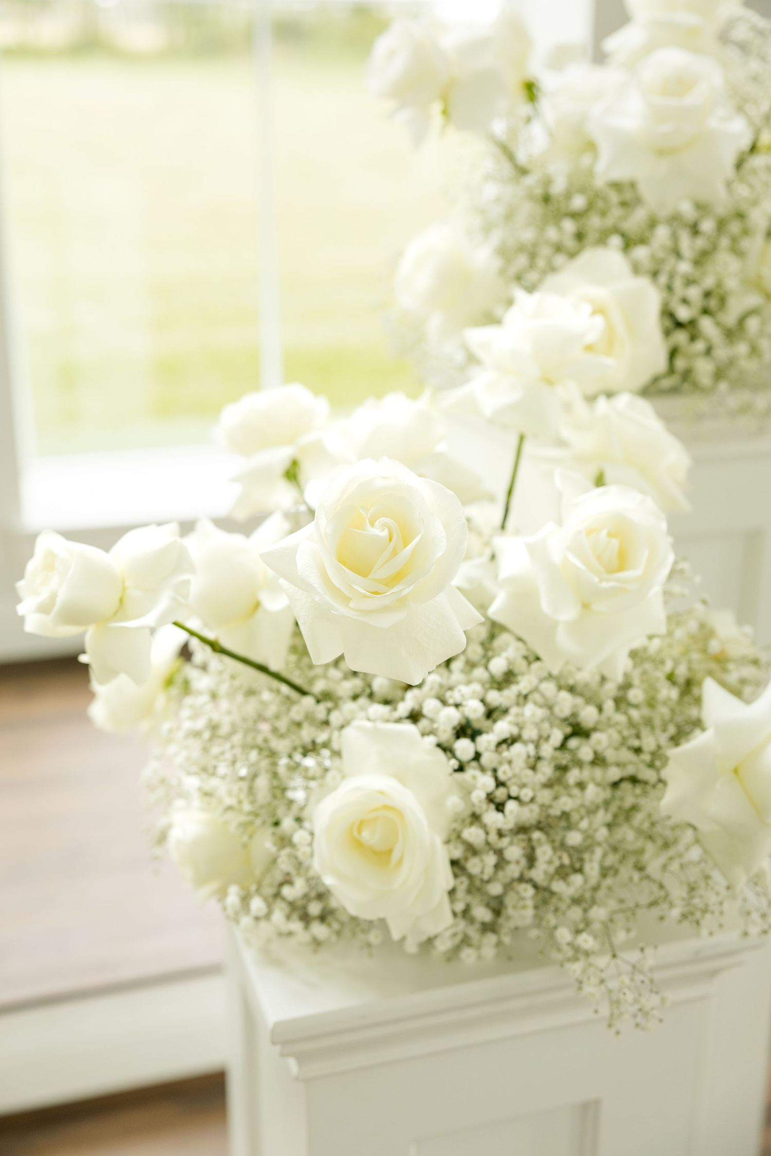 White roses and baby's breath floral arrangements in elegant white vases. Grand at the Springs.