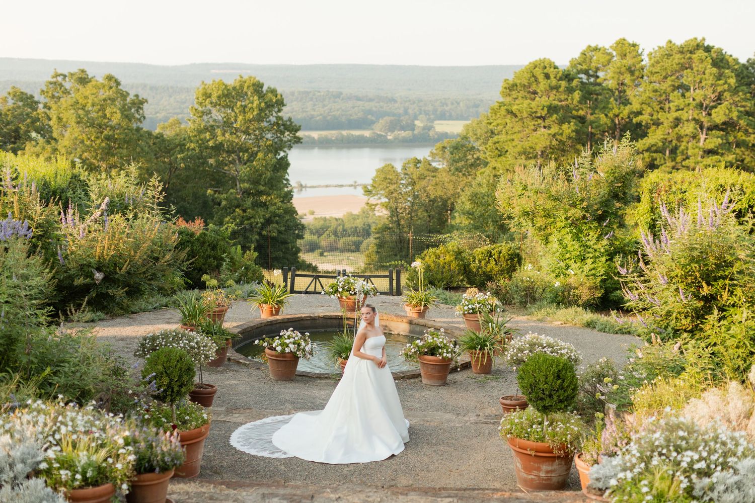 A scenic garden wedding photo overlooking a lake with potted plants and flowers. Moss Mountain Farm