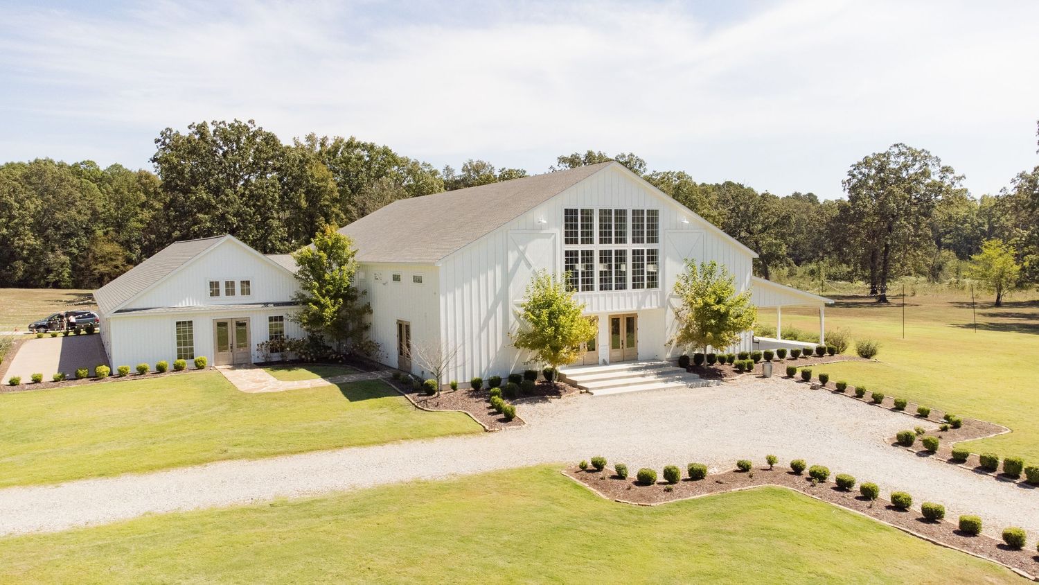 Aerial view of a modern white church building with large windows and landscaped grounds surrounded by trees.