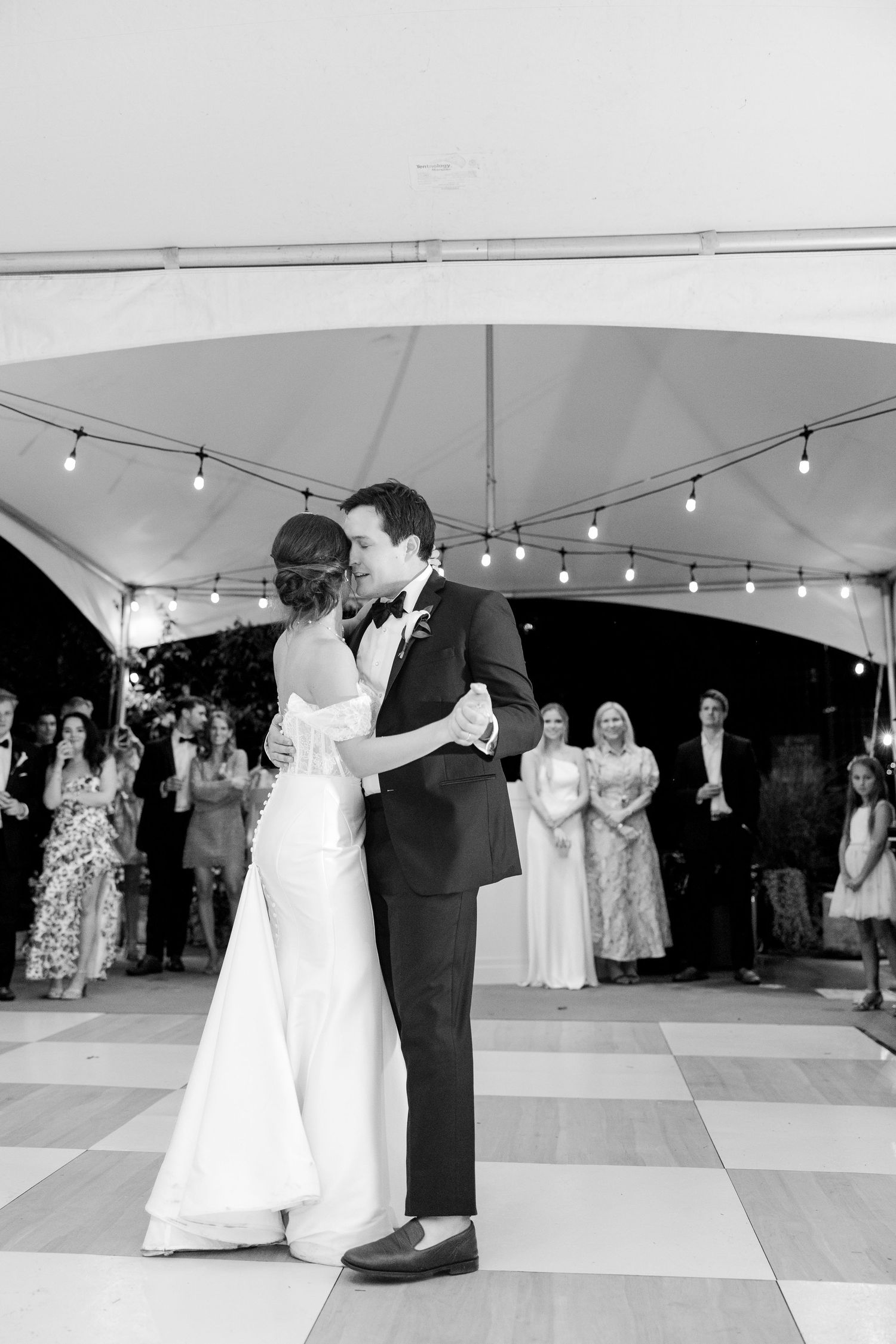 First dance under a white tent with string lights and guests watching from the dance floor.Botanical Gardens of the Ozarks