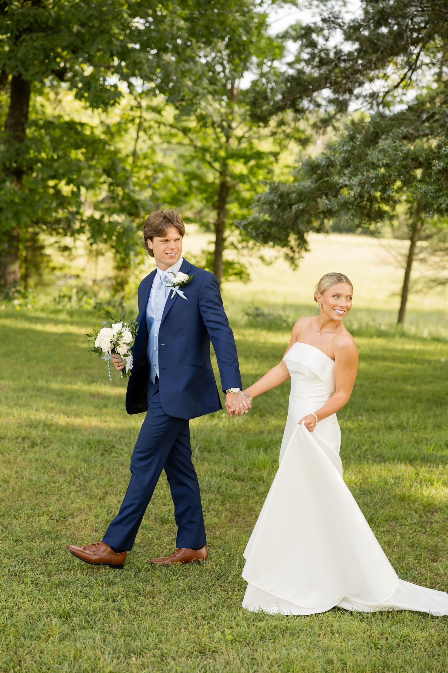 Playful wedding couple poses on green lawn during summer wedding photoshoot.Cold Springs Events