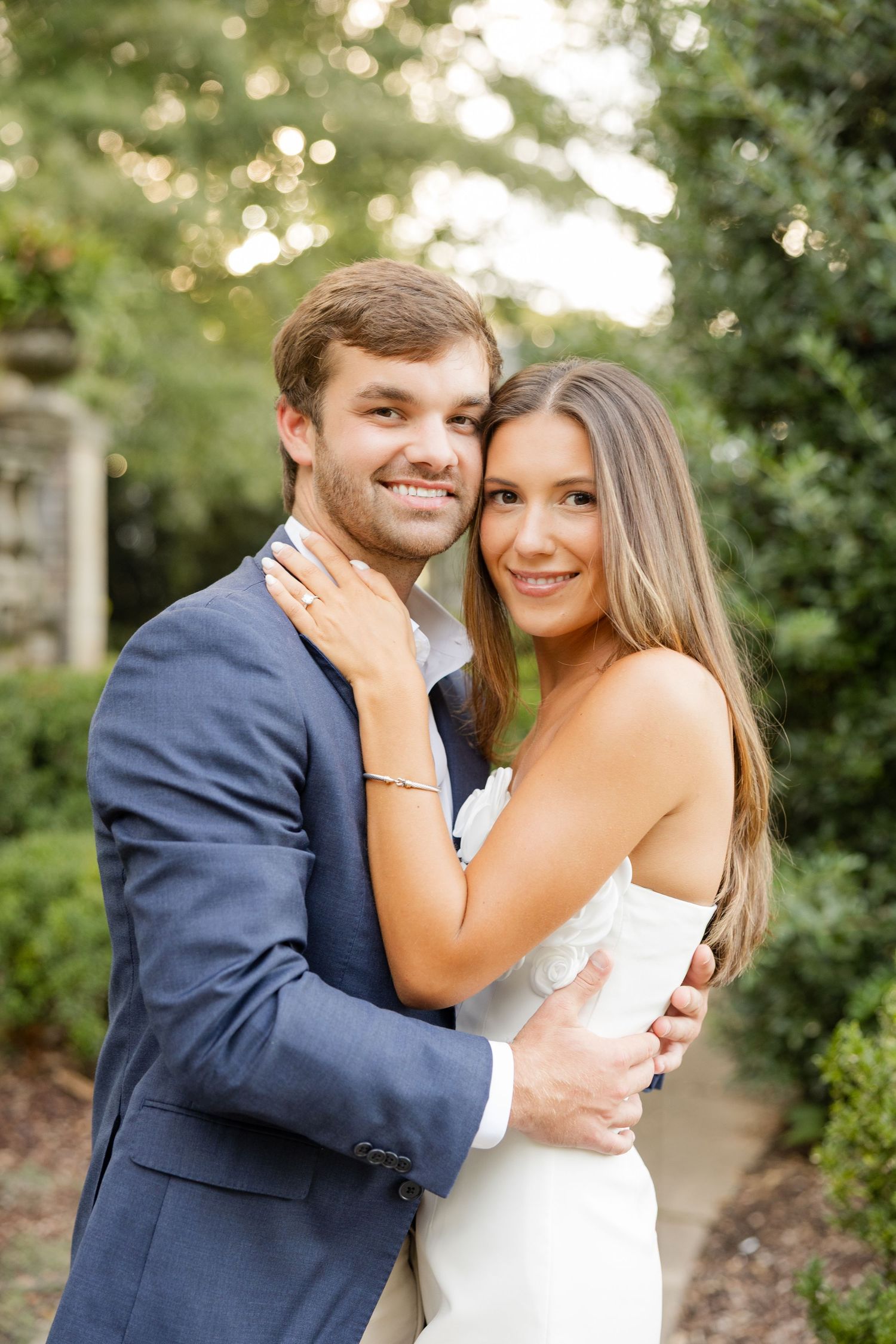 Romantic couple embracing in formal attire against a natural garden background.