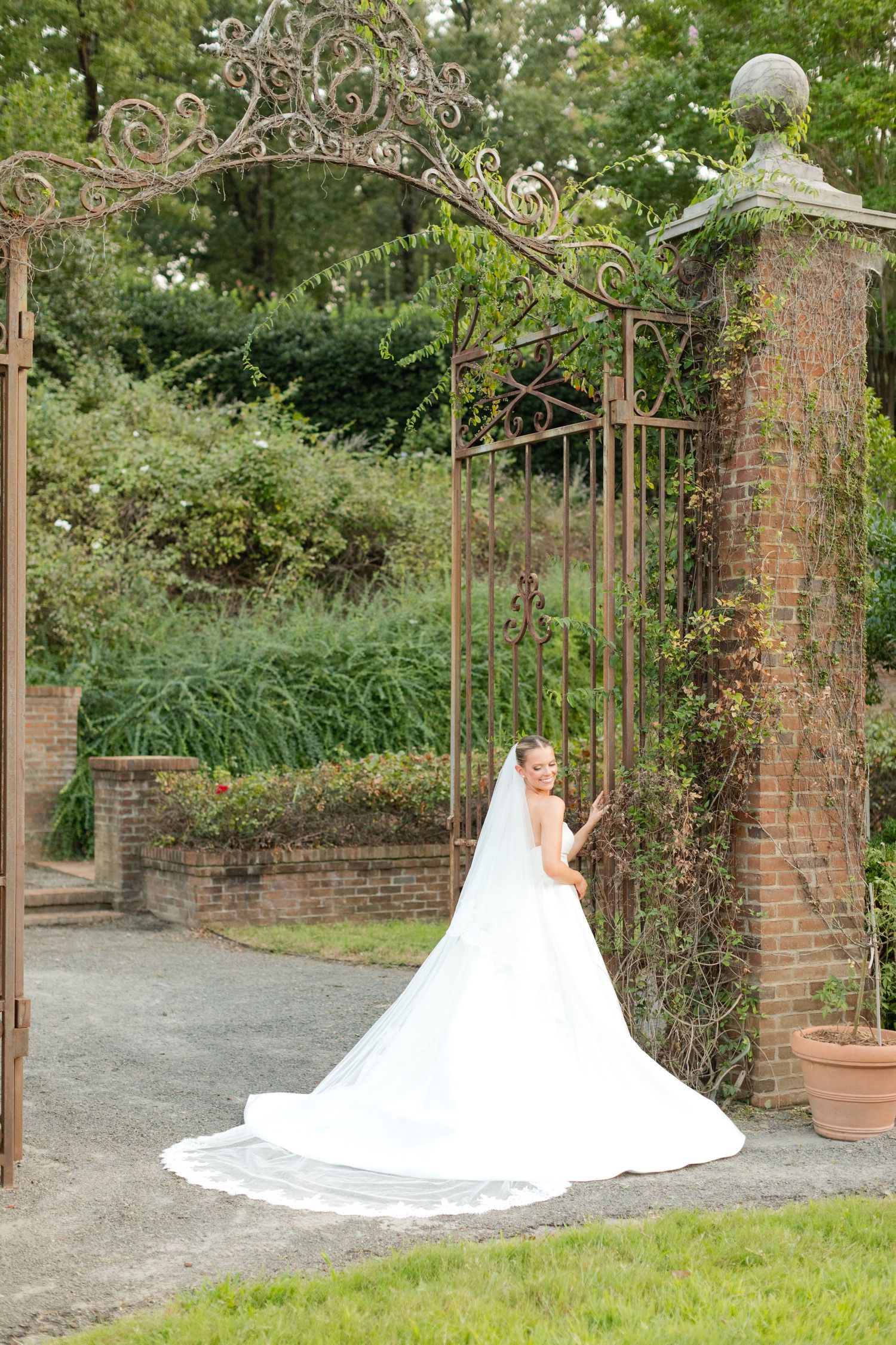 A white wedding dress silhouette against rustic brick pillars and garden archways.
