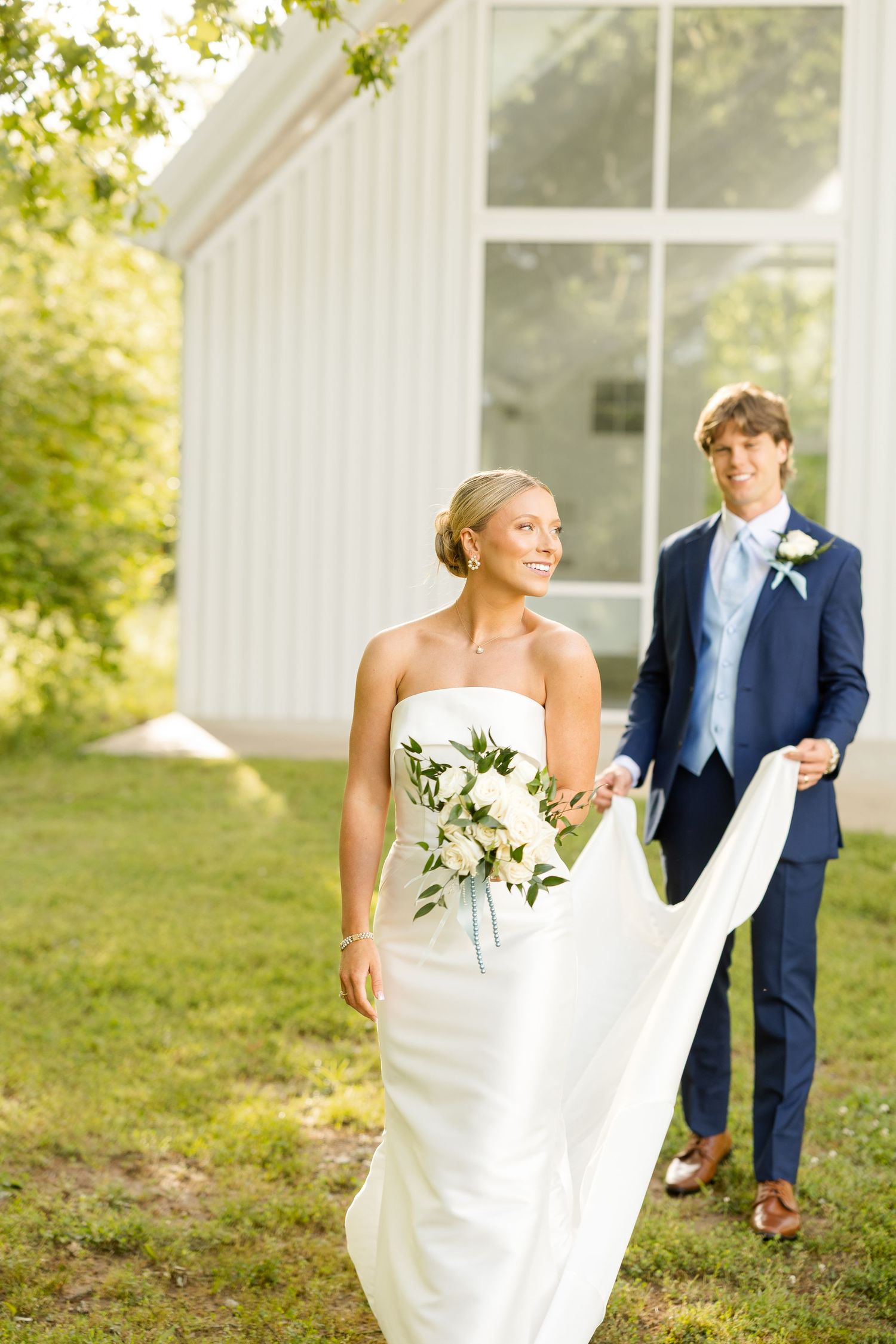 A couple takes romantic outdoor wedding photos against a white chapel backdrop.Cold Springs Events.