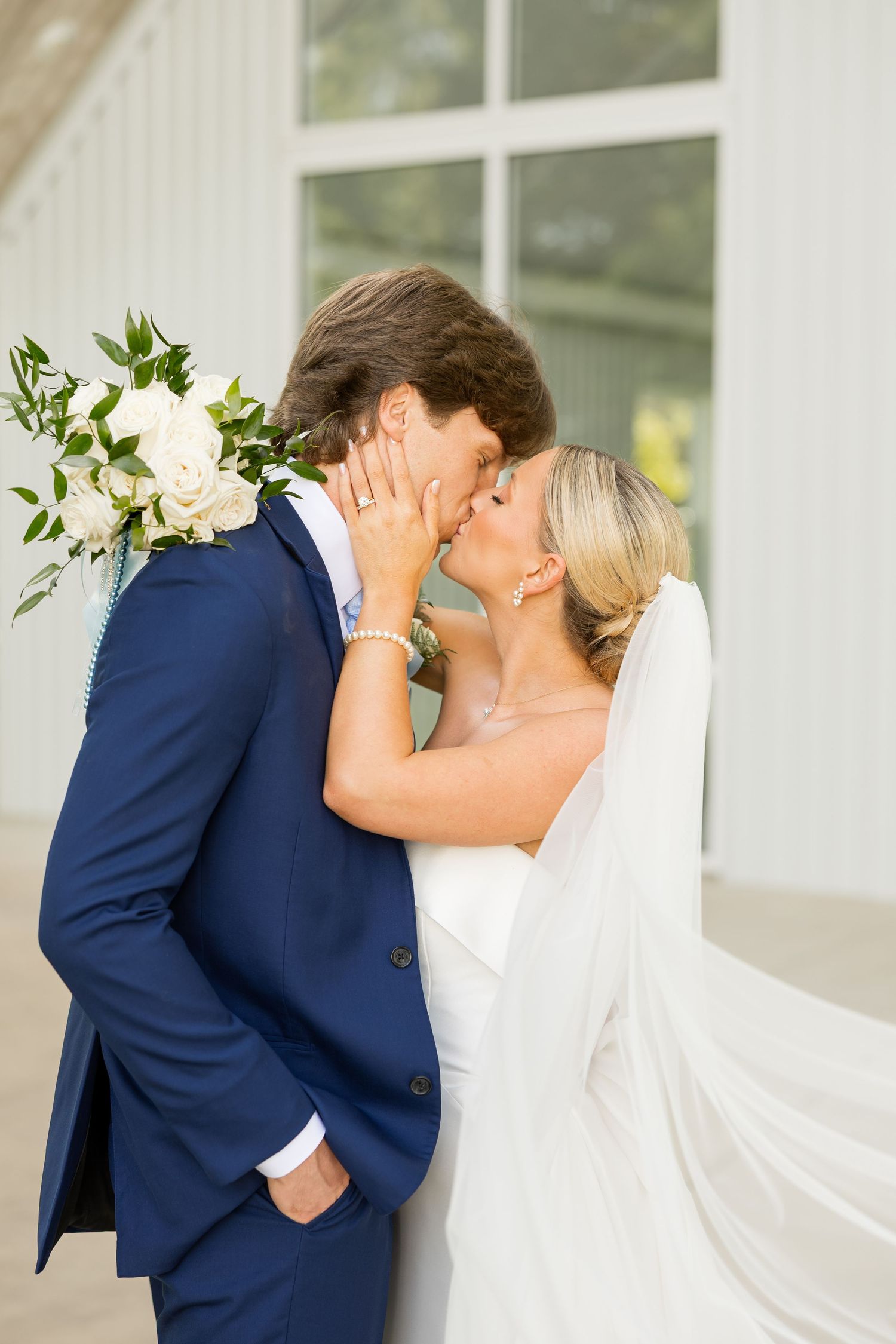 Romantic wedding couple sharing a tender moment in front of white pillars.Cold Springs Events