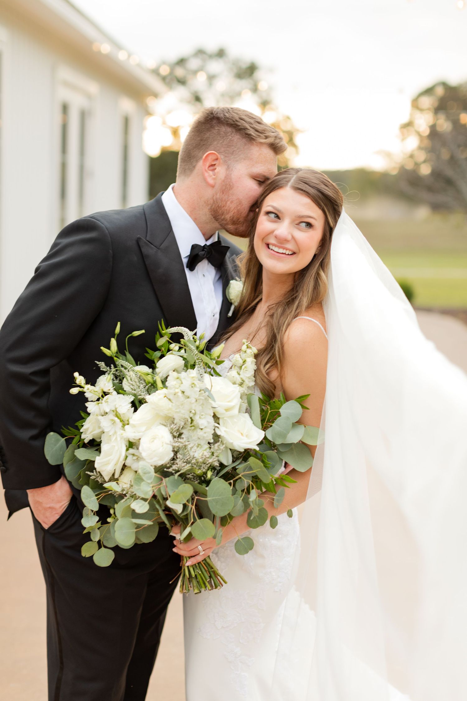 An intimate wedding portrait featuring a beautiful white bouquet with eucalyptus leaves.