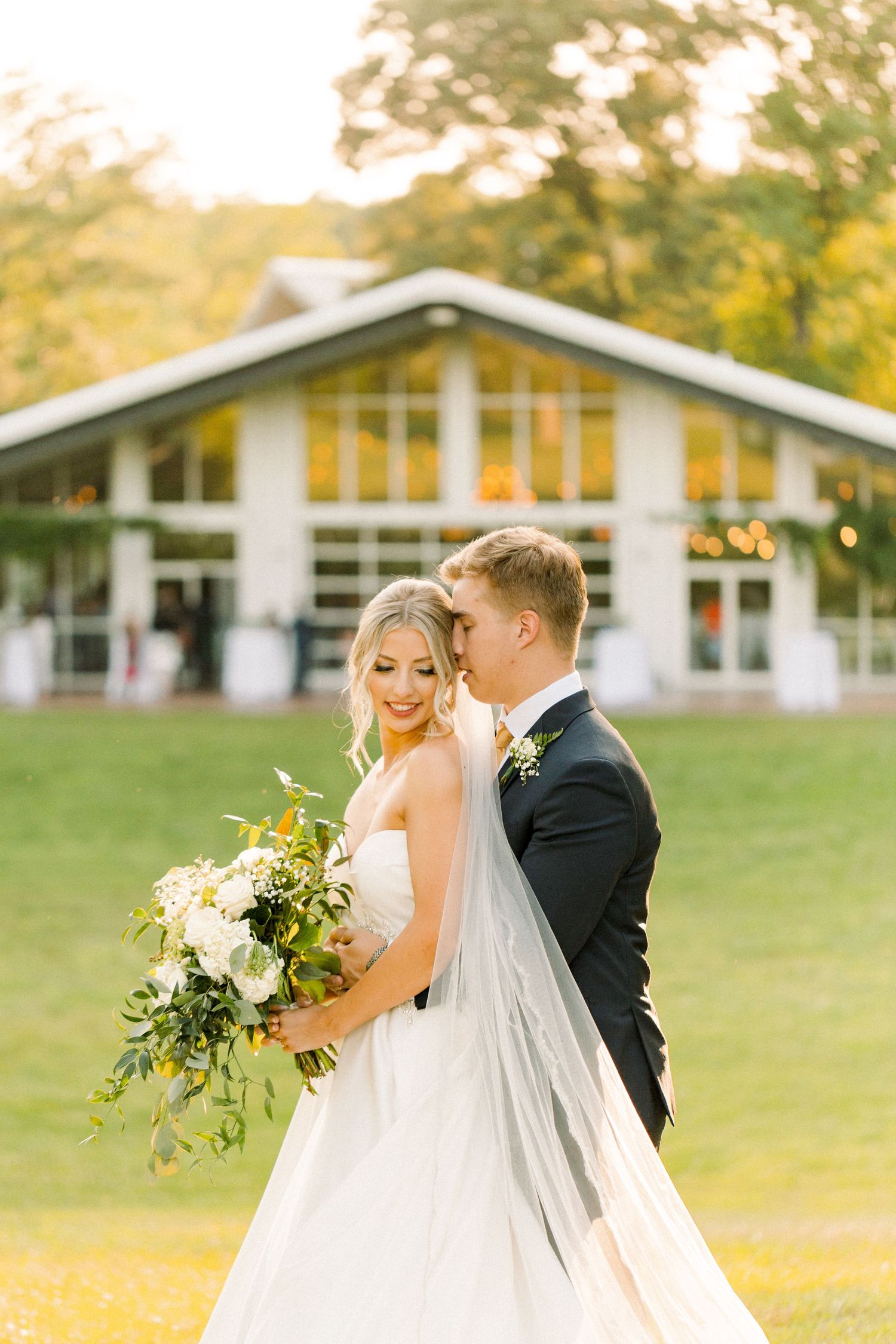 Newlyweds share intimate moments against a backdrop of rustic white buildings during golden hour. Cold Springs