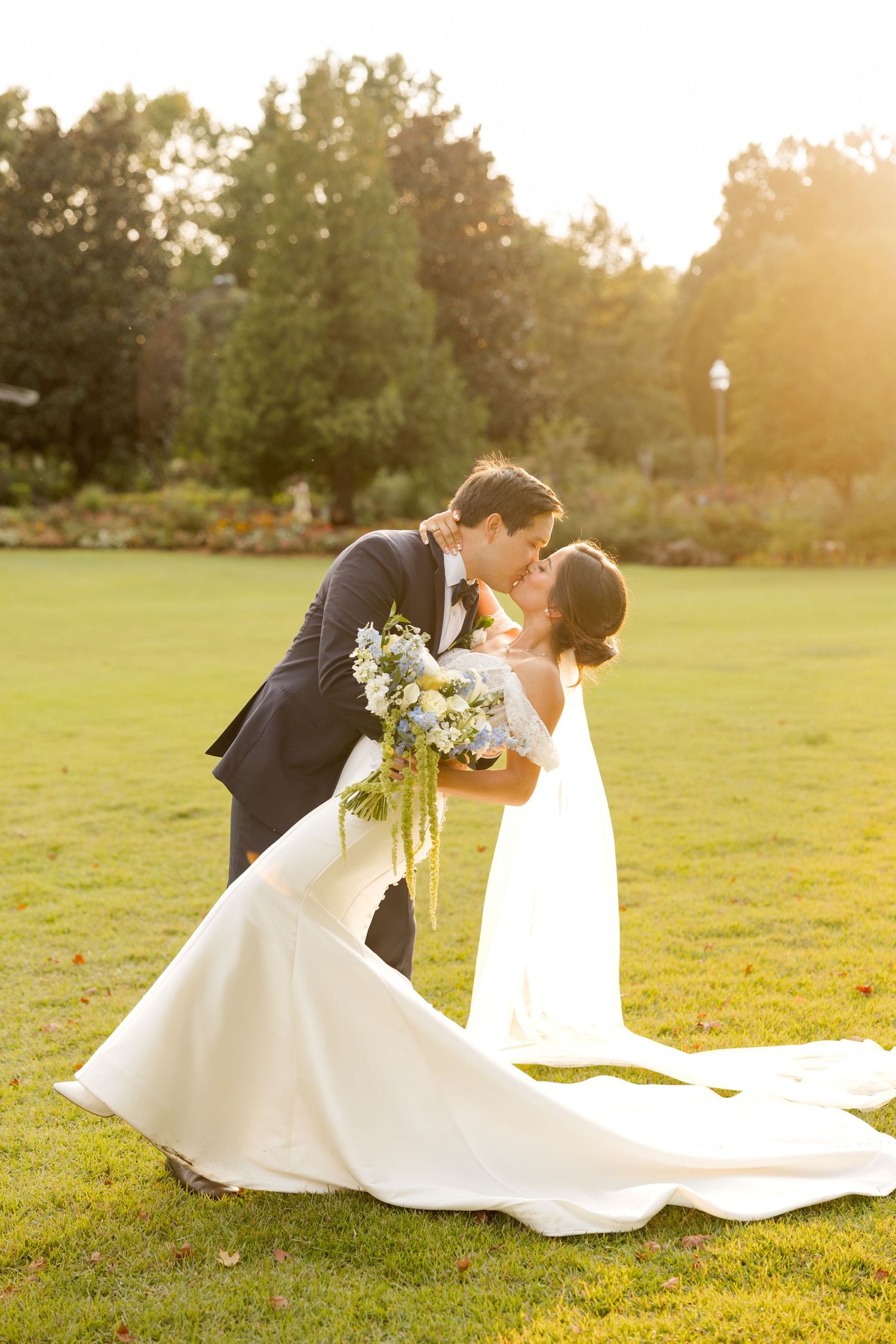 Sunset wedding portrait on a manicured lawn with a flowing white dress and yellow bouquet. Botanical Gardens of the Ozarks