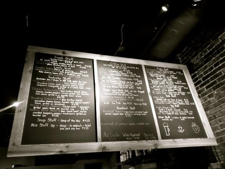 A series of black chalkboard menus mounted on a wall display handwritten text in white chalk.