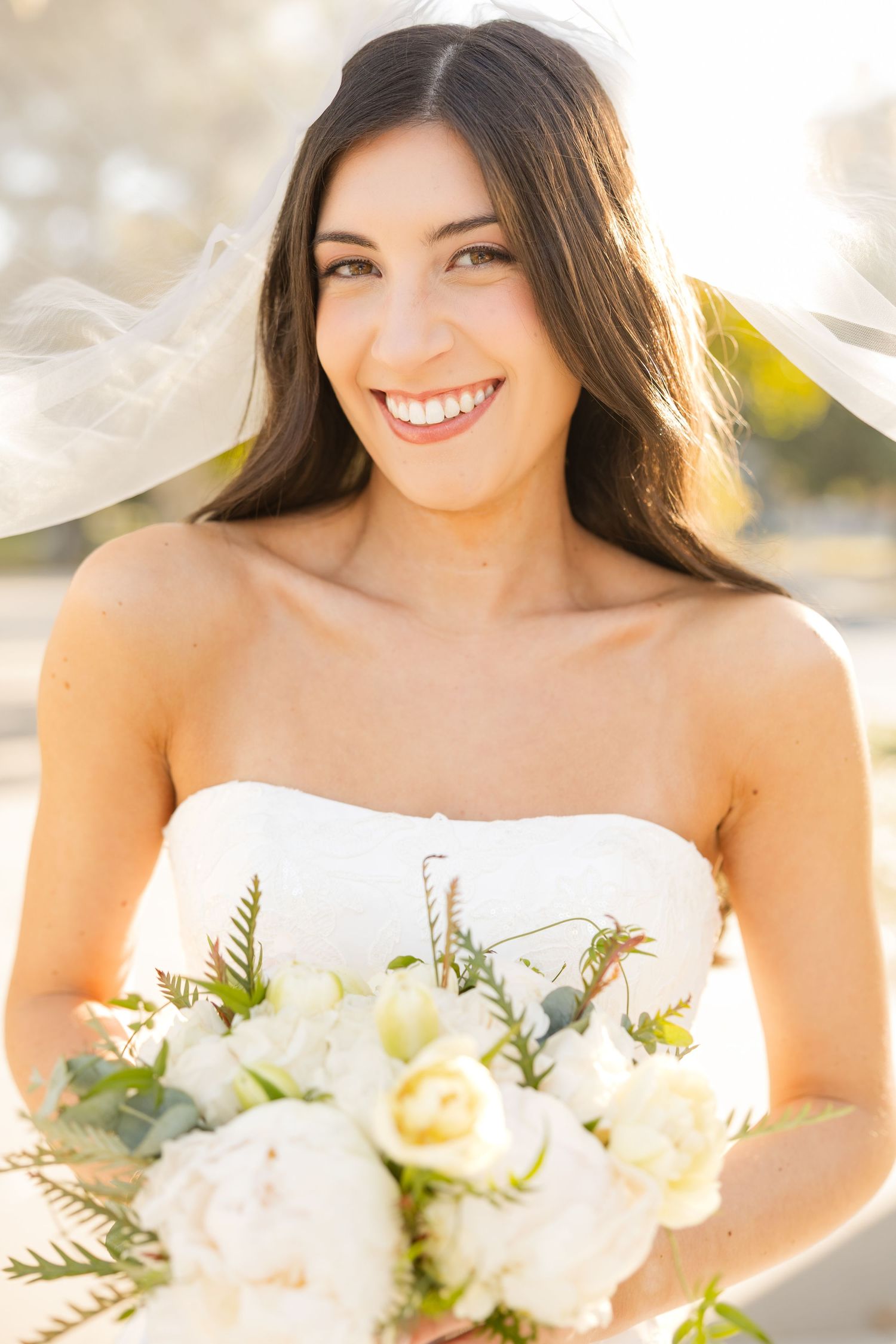 A bright and cheerful bridal portrait series showing a white wedding bouquet in natural sunlight.