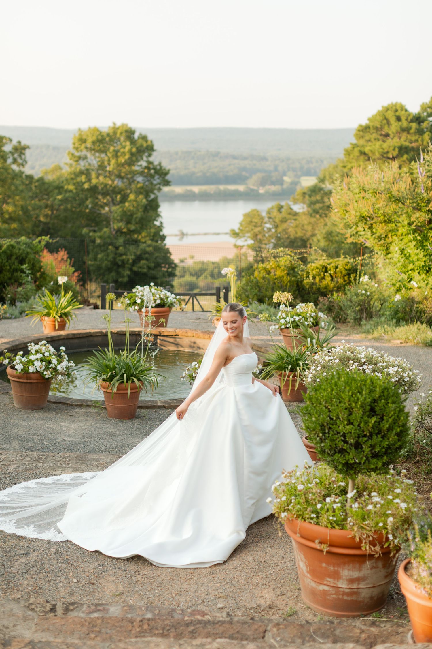 Elegant bridal portraits in a garden terrace overlooking scenic views with potted plants and natural landscaping.