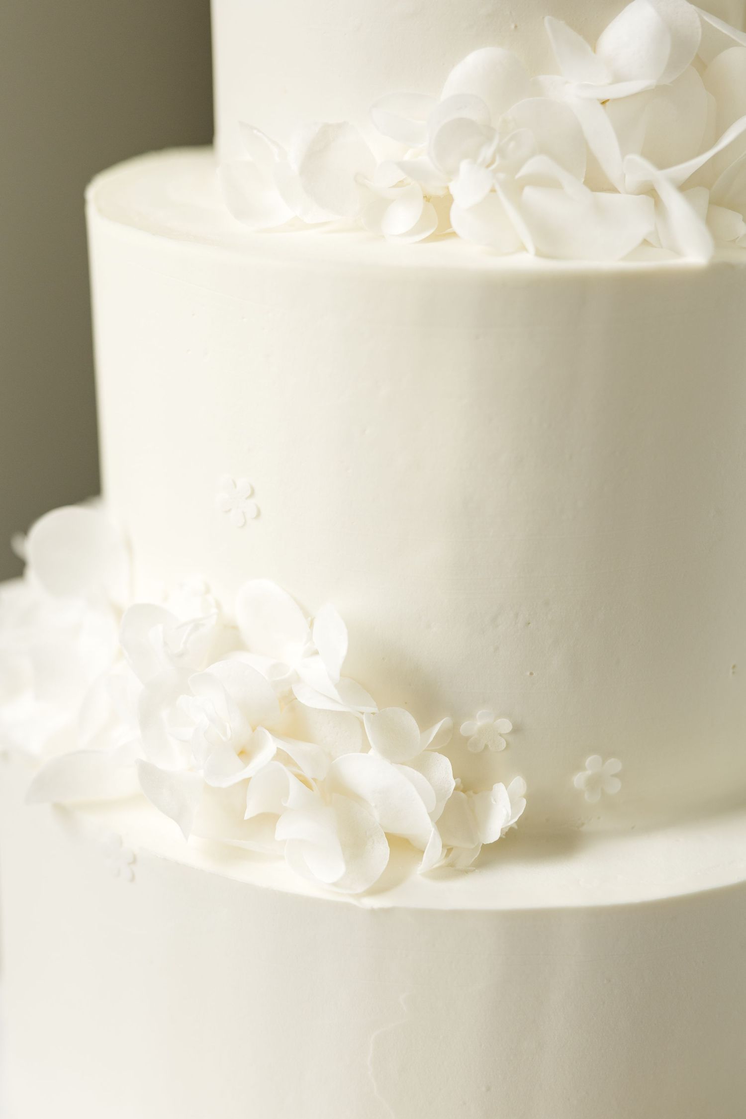 Close-up of white wedding cake tier decorated with elegant sugar flowers. Cold Springs Events