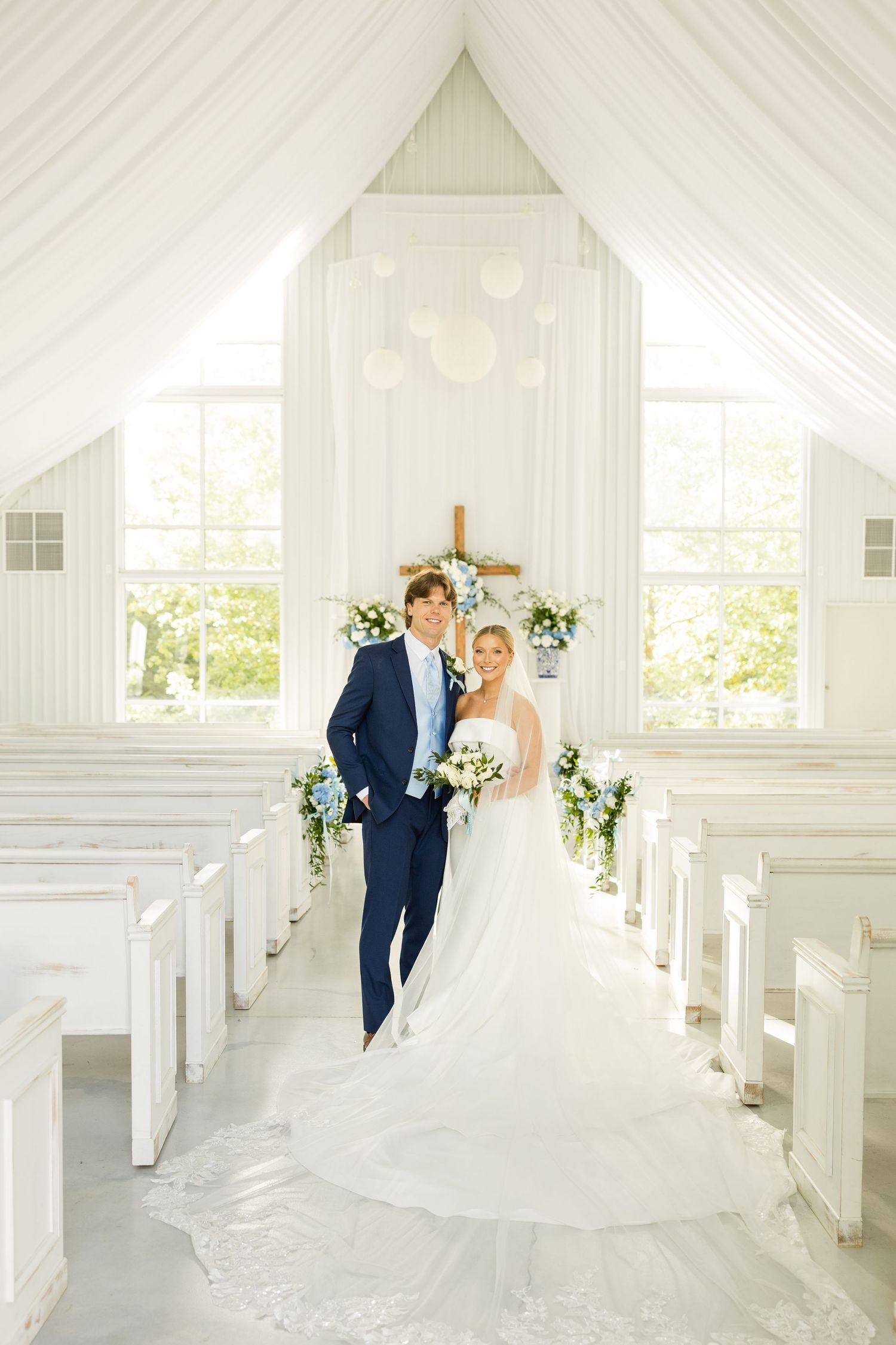 Bright white chapel interior with draped fabric and windows creating an ethereal wedding ceremony space.Cold Springs Events