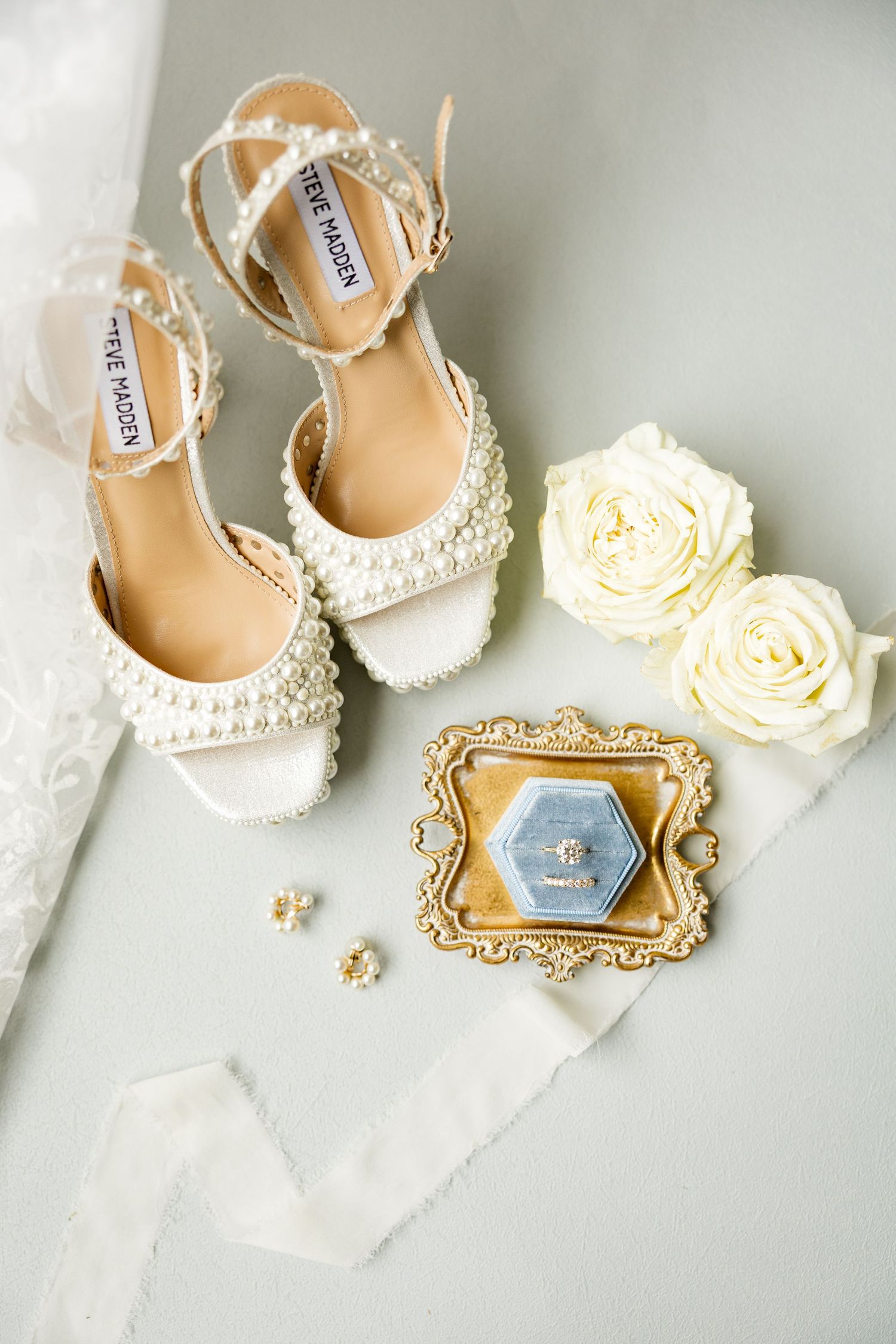 Elegant pearl-embellished bridal shoes displayed with white roses and vintage frames. Cold Springs Events