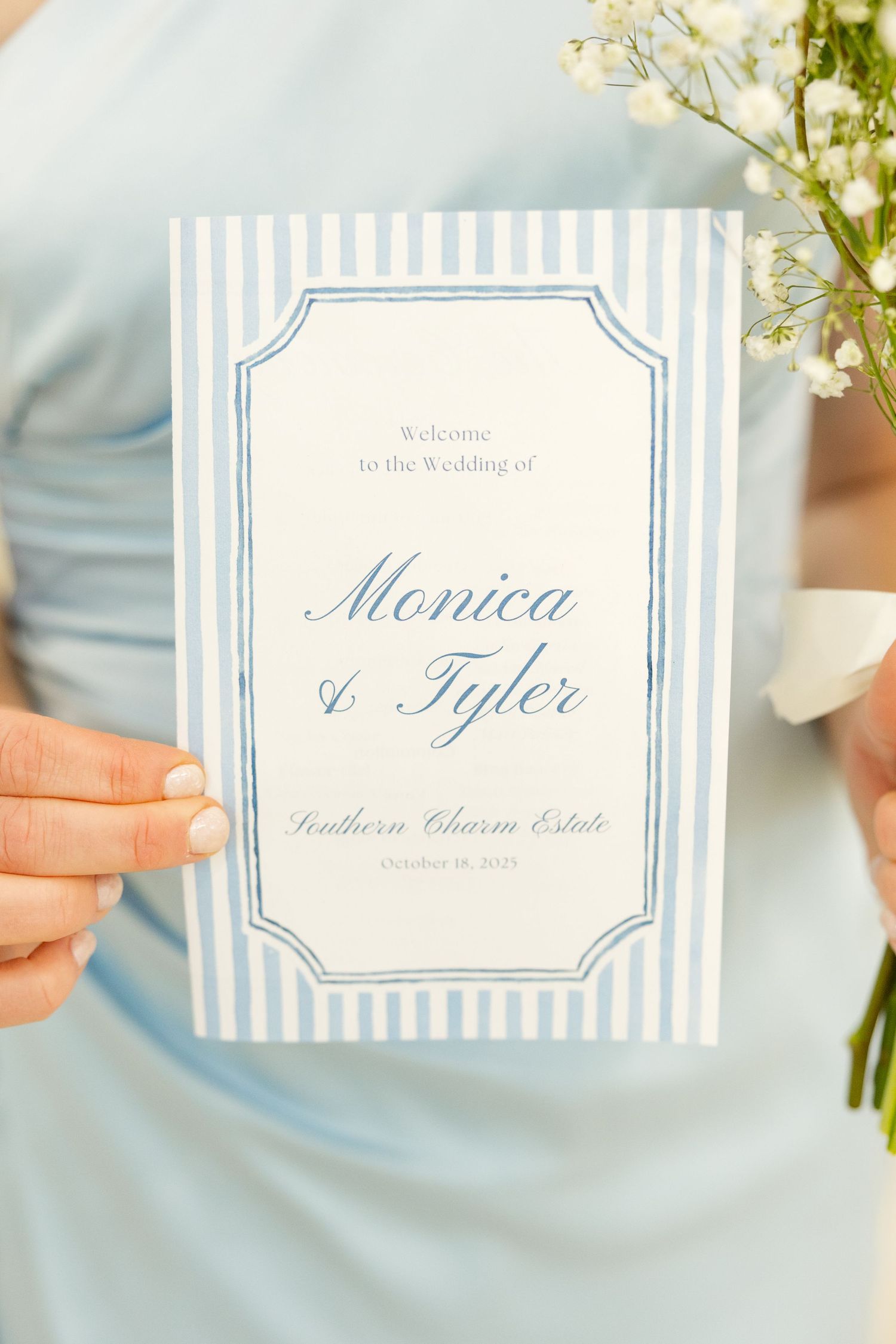 Elegant wedding program with blue stripes and calligraphy for Monica and Tyler's ceremony being held by someone in blue.