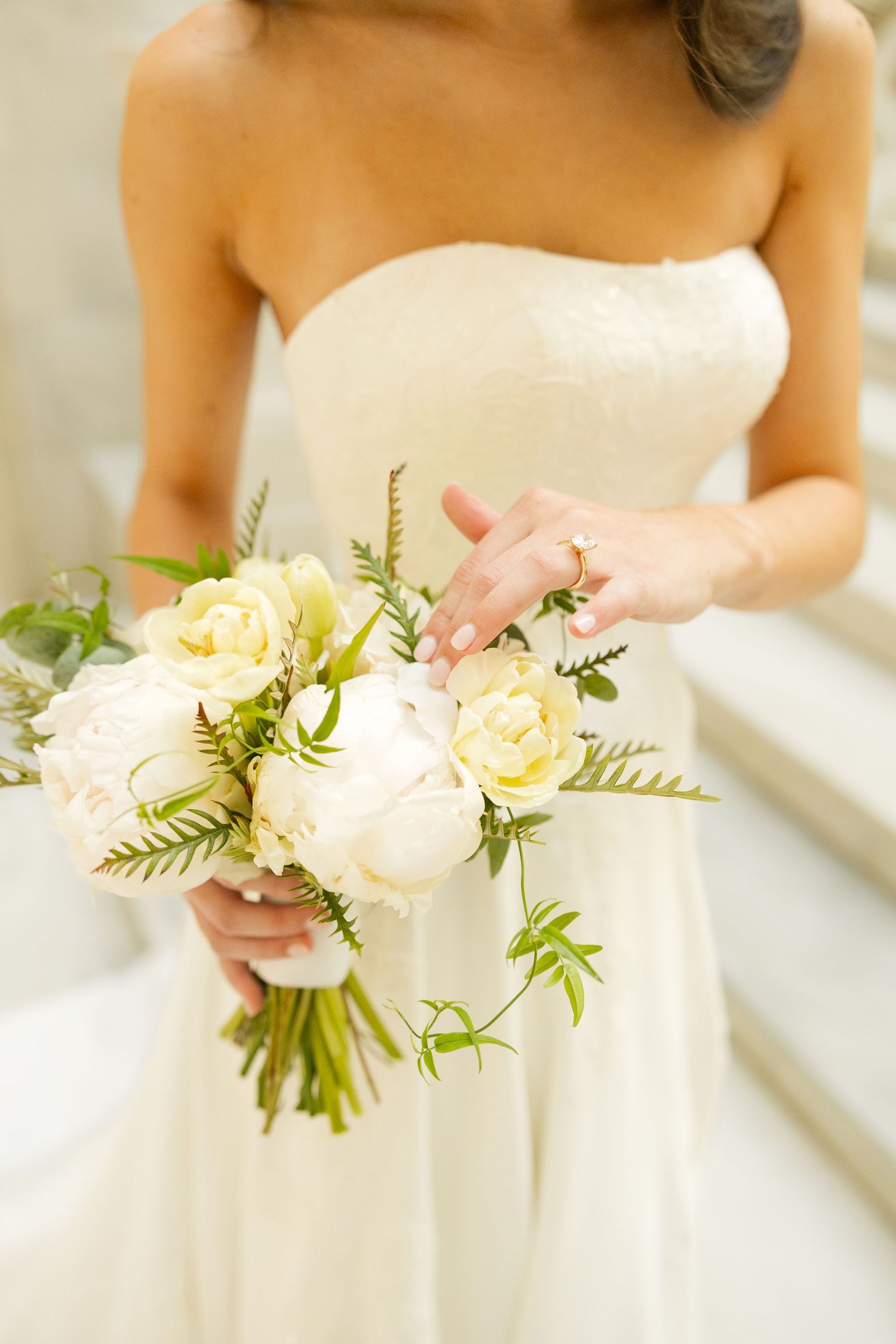 Close-up details of a white and yellow wedding bouquet with fresh greenery and roses.