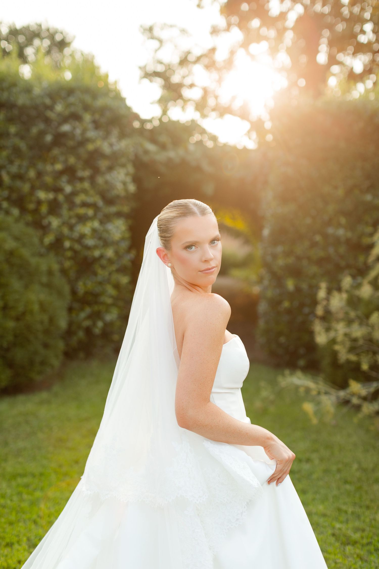 Ethereal bridal portraits in a garden setting during golden hour with a flowing white veil.