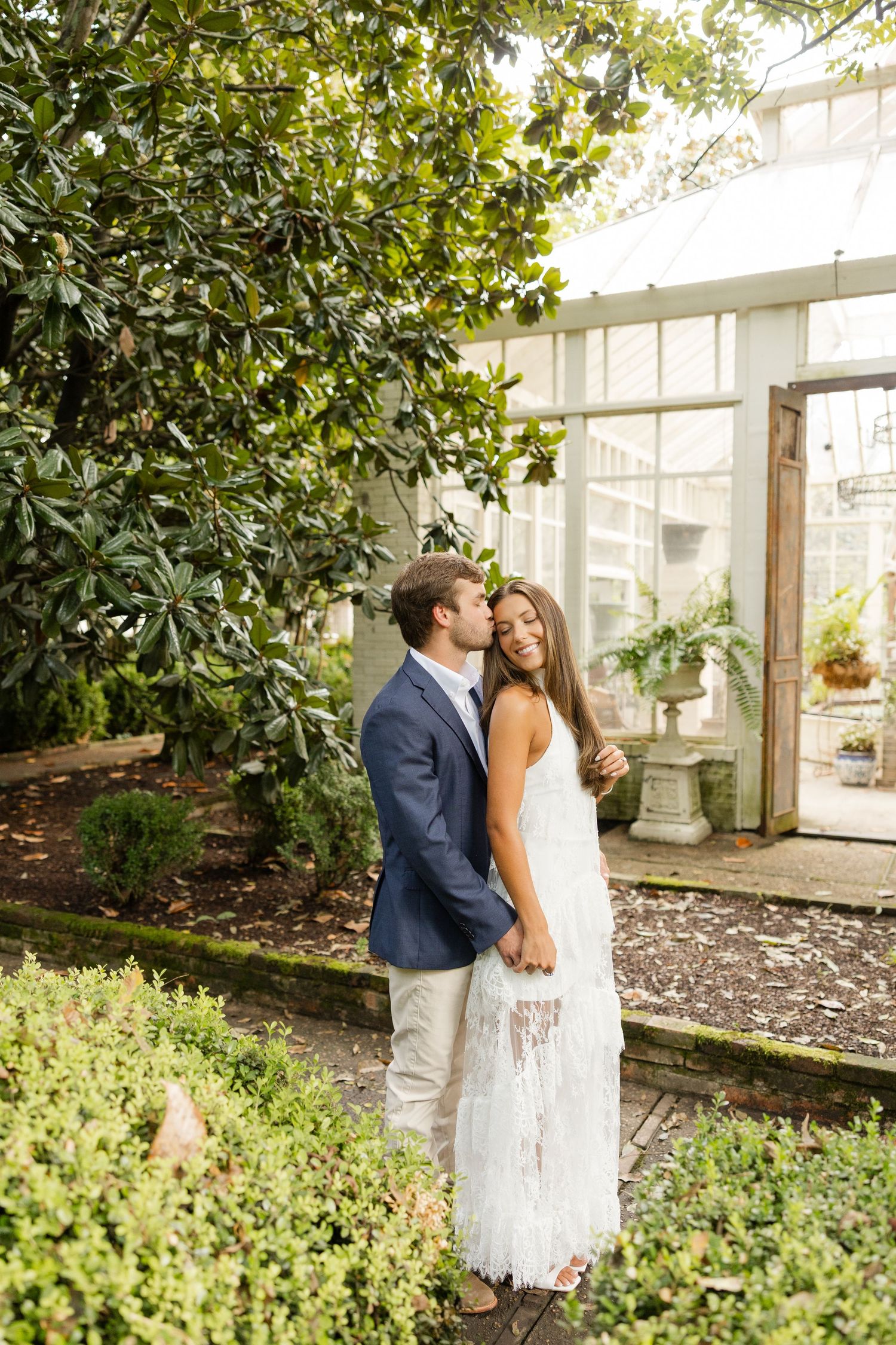 Intimate garden wedding portraits captured in a lush greenhouse setting with natural light filtering through.