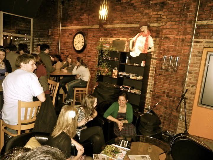 People enjoying drinks and conversation at a rustic brick-walled bar with warm lighting and cozy ambiance.