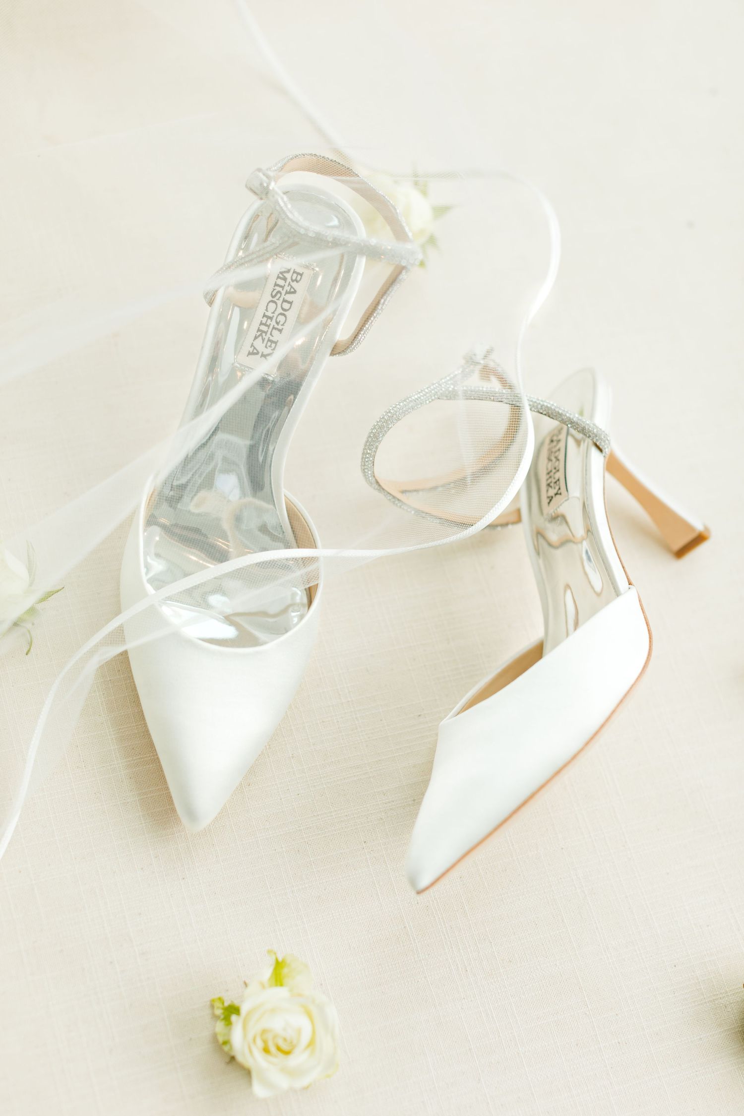 Elegant white bridal heels with strappy details and a small rose accent.