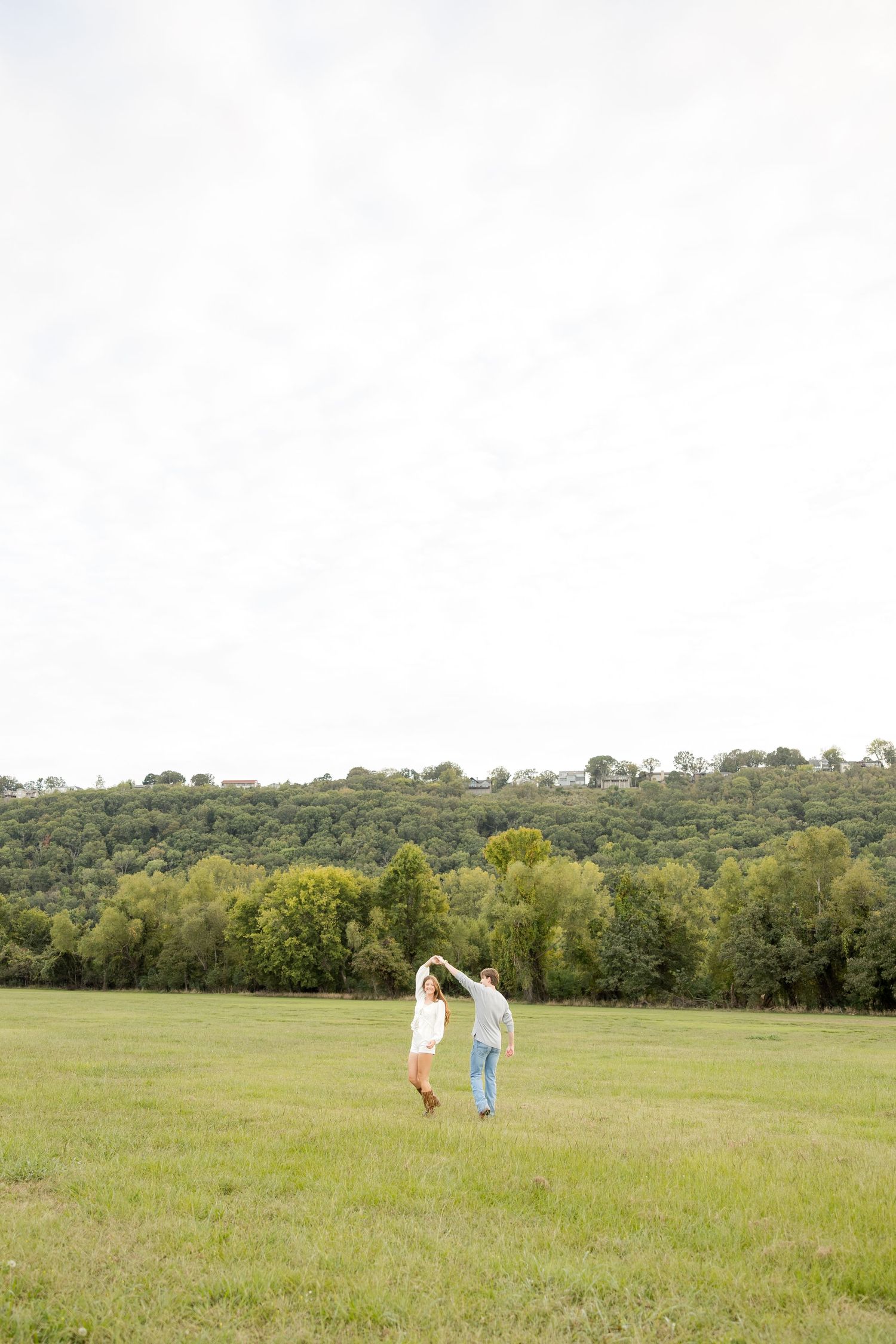 A panoramic view of a green meadow with distant figures walking across the open field.