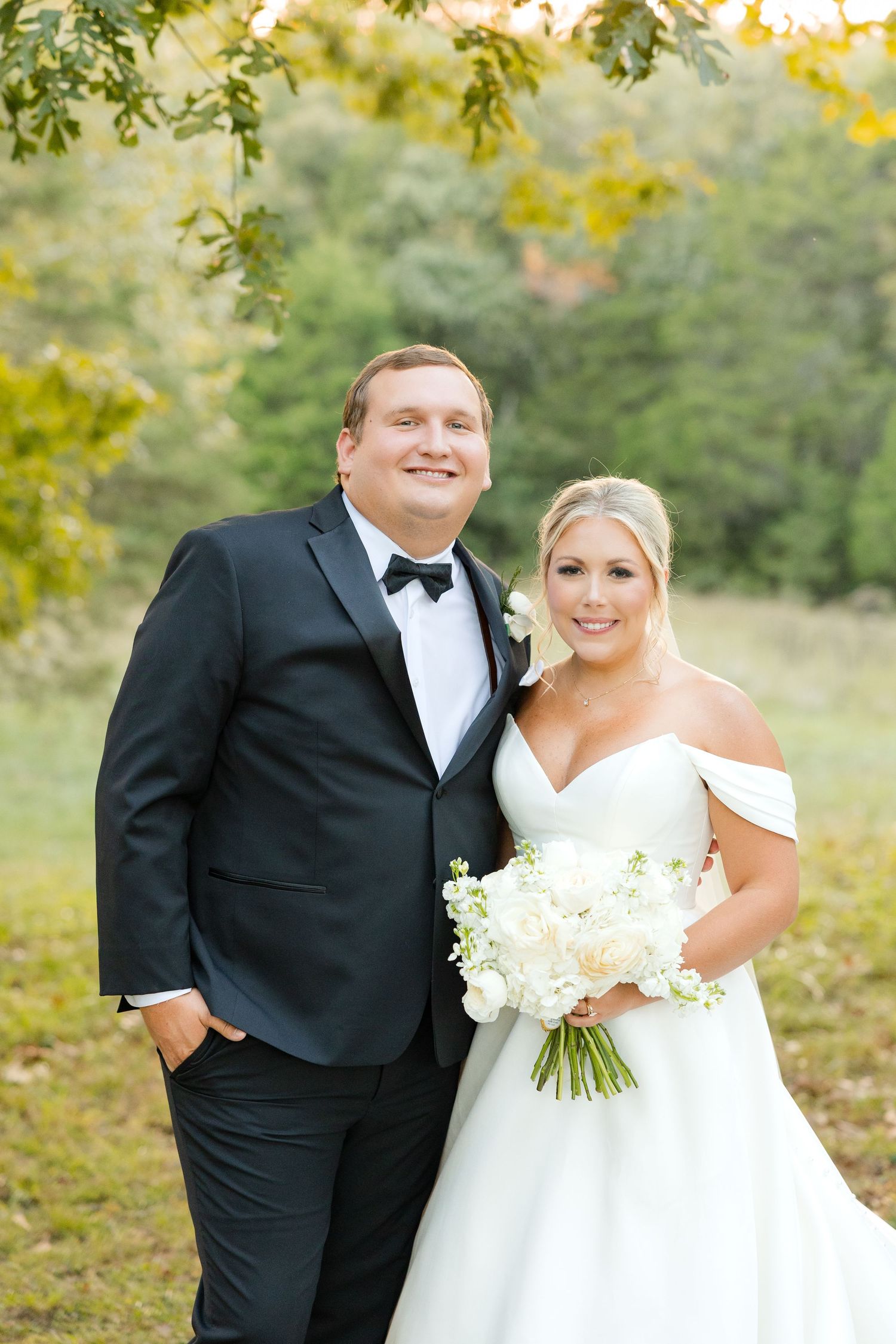 A couple poses together outdoors in formal wedding attire with autumn foliage in the background. Cold Springs Events.