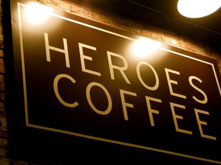 A row of illuminated coffee shop signs glows warmly against a dark background.