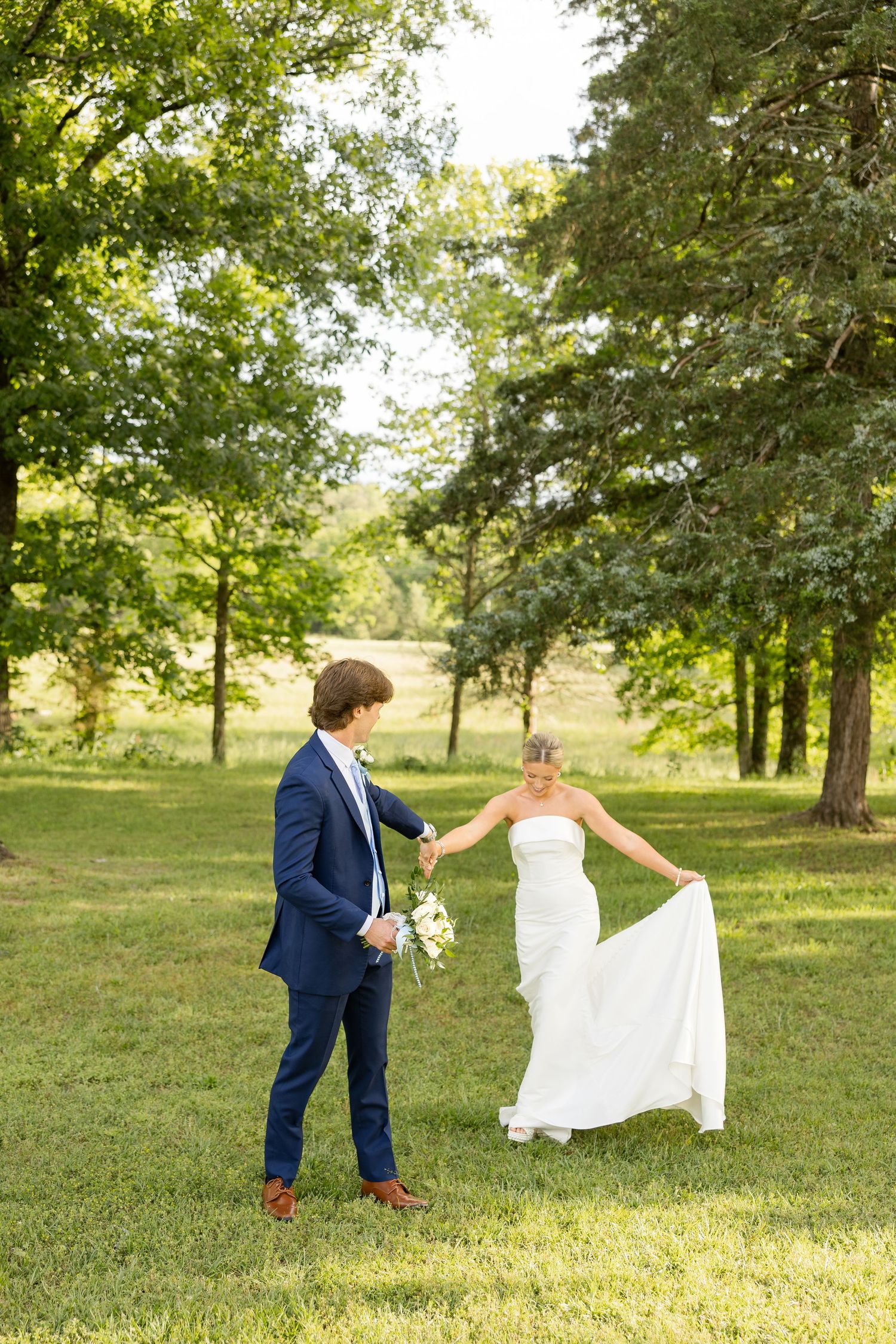 Couple taking playful photos on grassy lawn with sunlight filtering through trees.Cold Springs Events