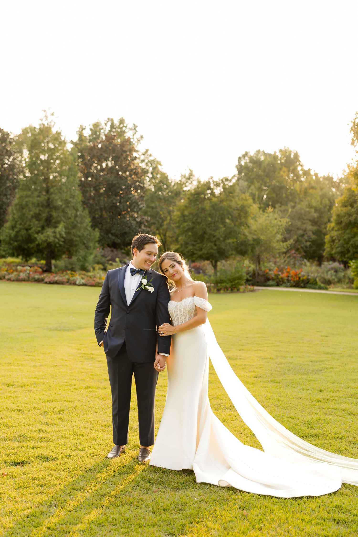 Sunset wedding portrait on a green lawn with long flowing veil and classic formal attire.Botanical Gardens of the Ozarks