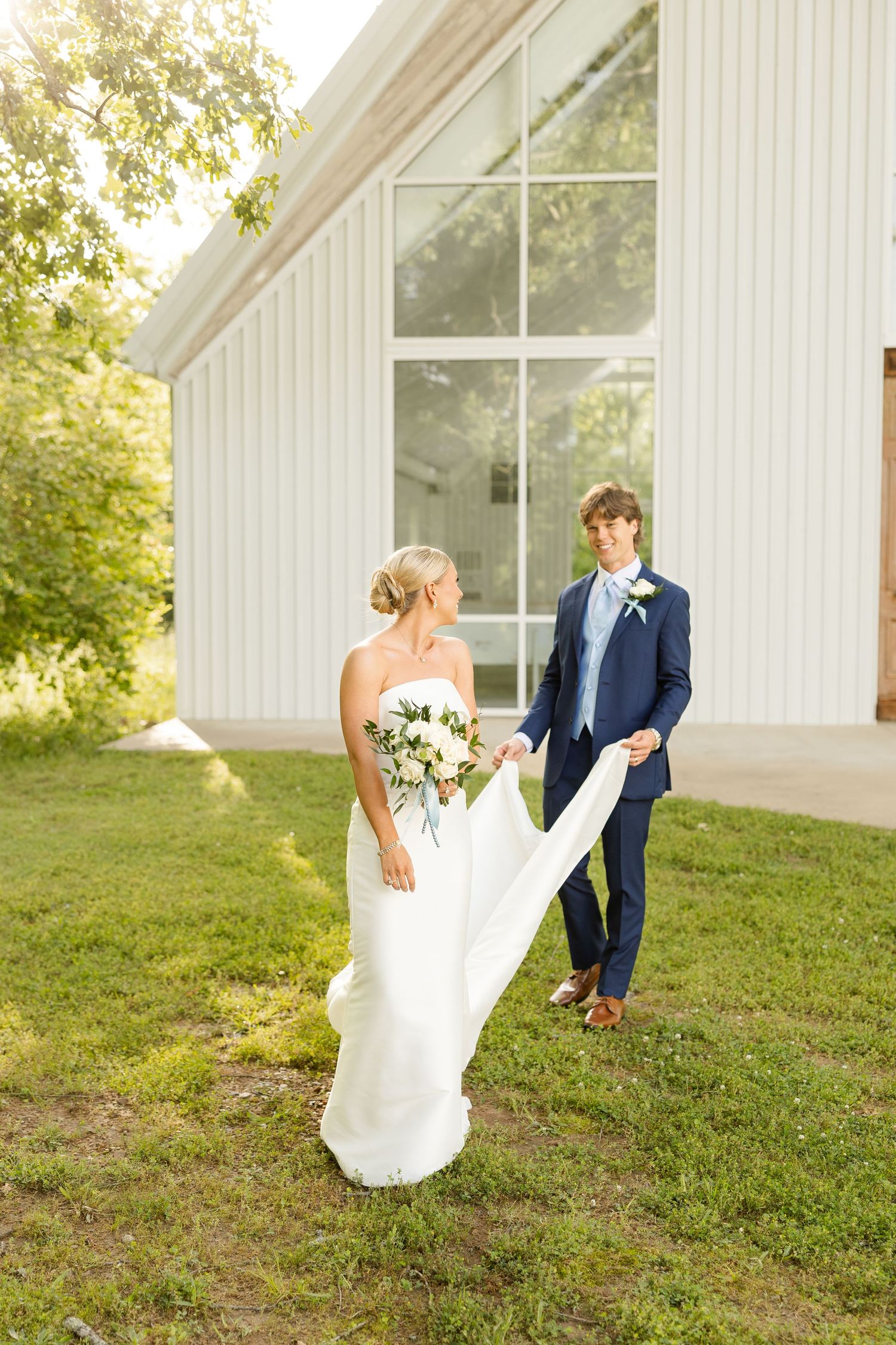 A couple poses outside a white chapel as the bride's dress flows in the breeze.Cold Springs Events
