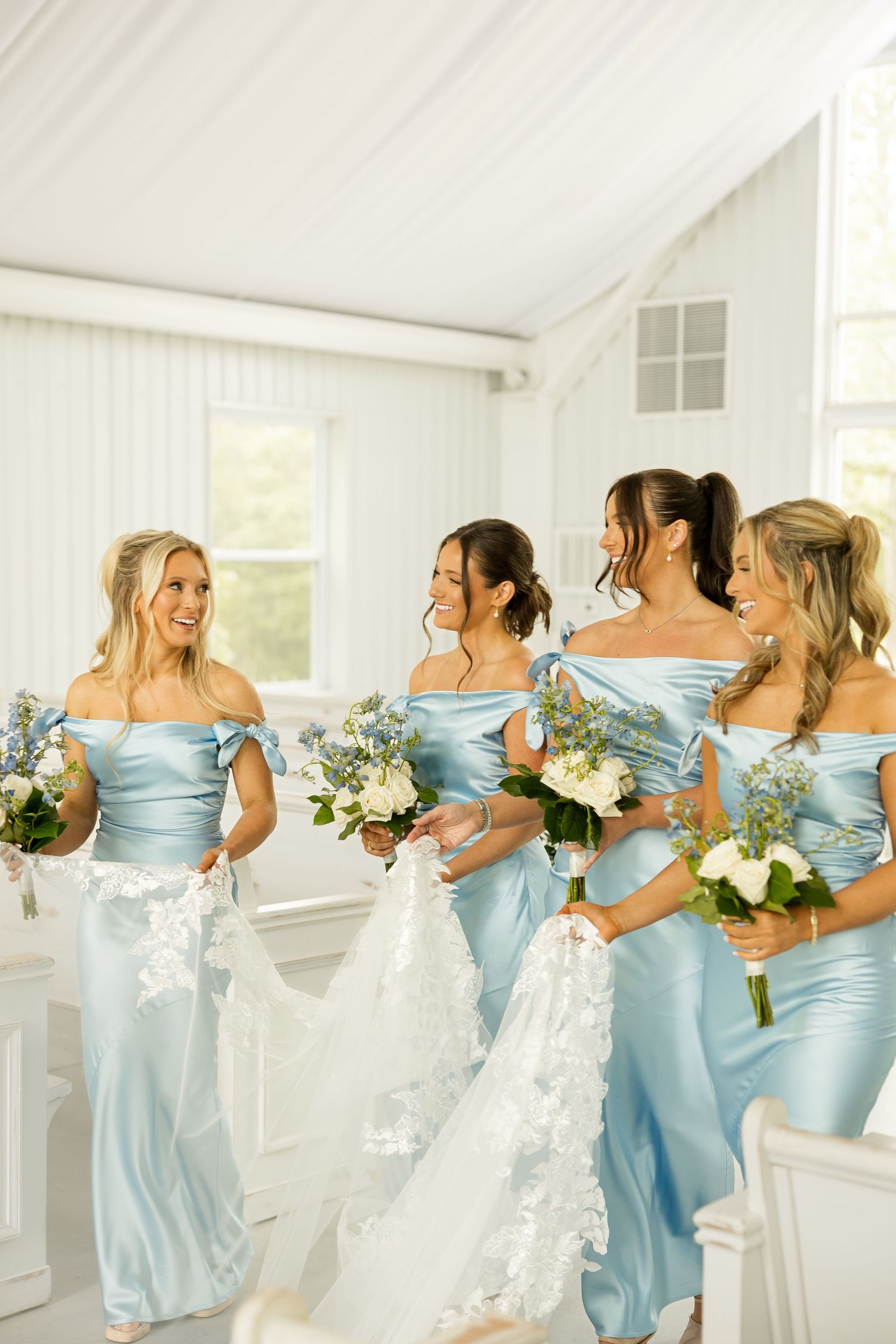 Bridesmaids in powder blue satin dresses holding white floral bouquets. Cold Springs Events