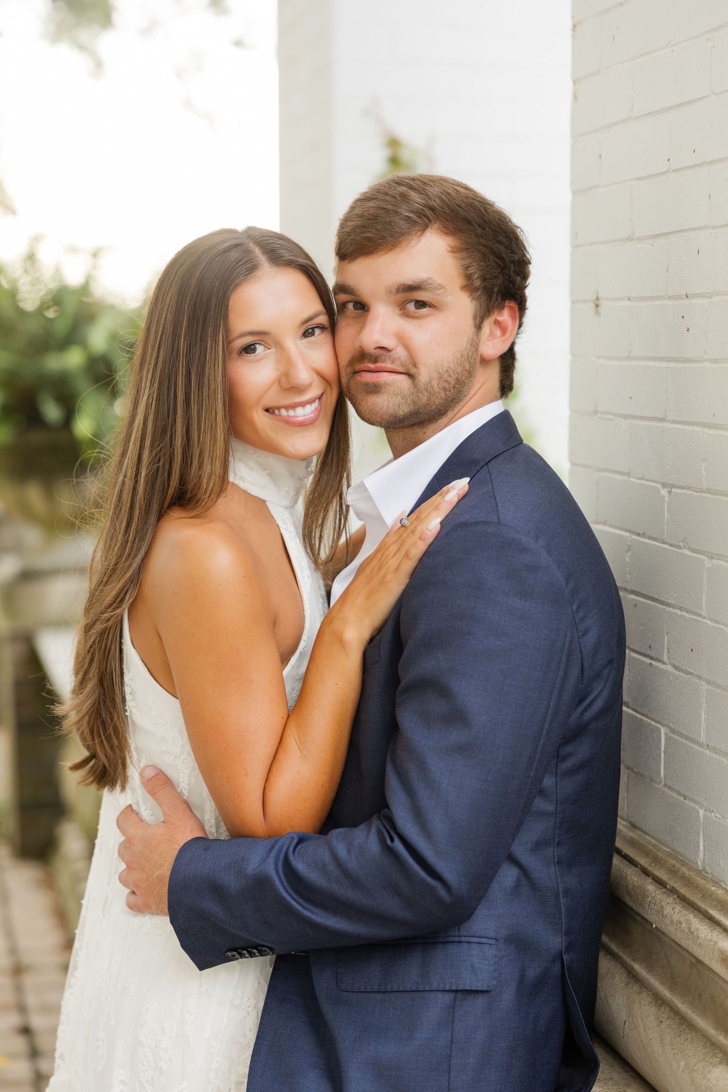 A series of intimate wedding portraits showing a couple embracing against a white wall backdrop outdoors.