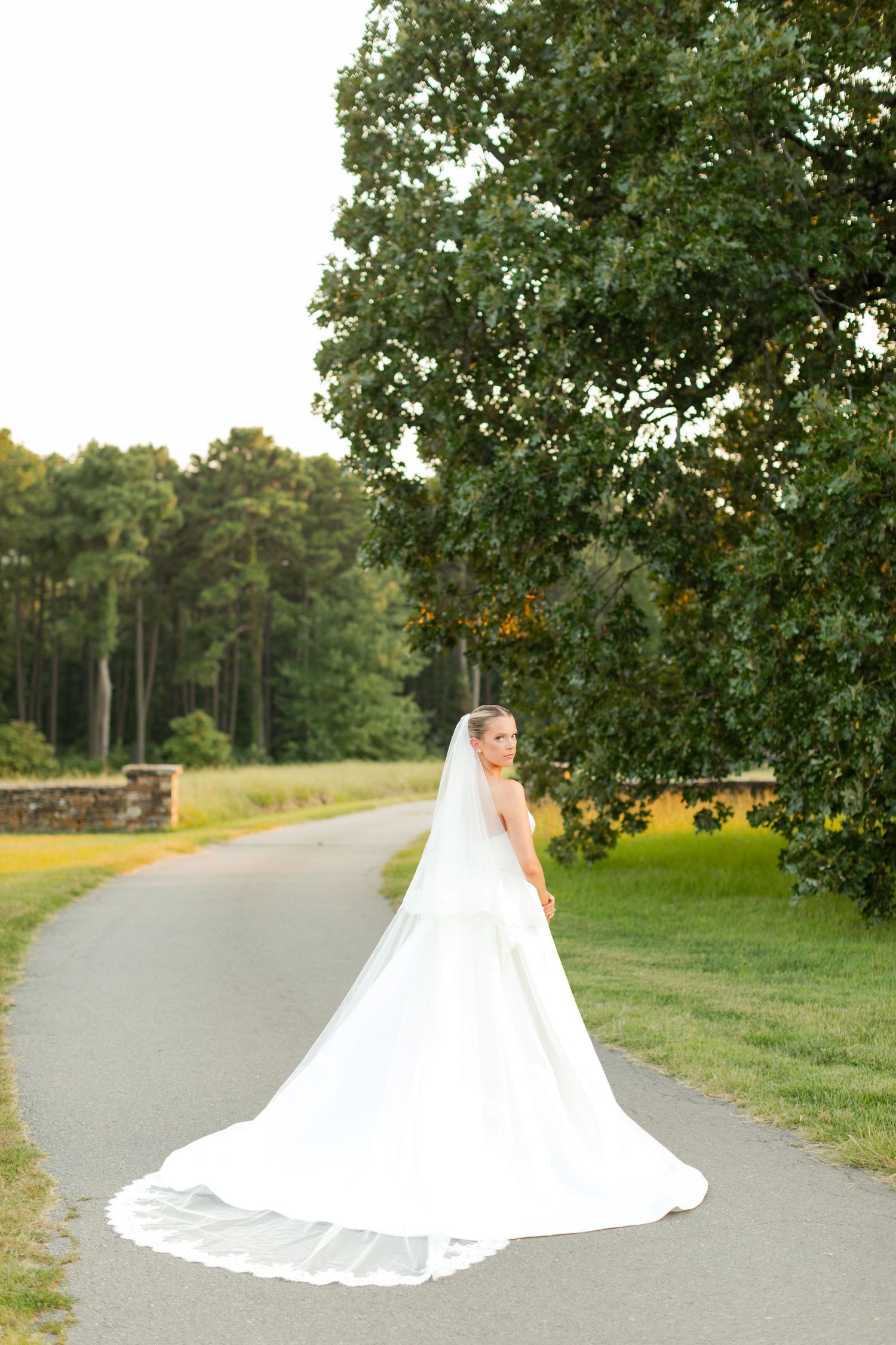 Elegant bridal portrait on a winding path with a flowing white wedding gown train.