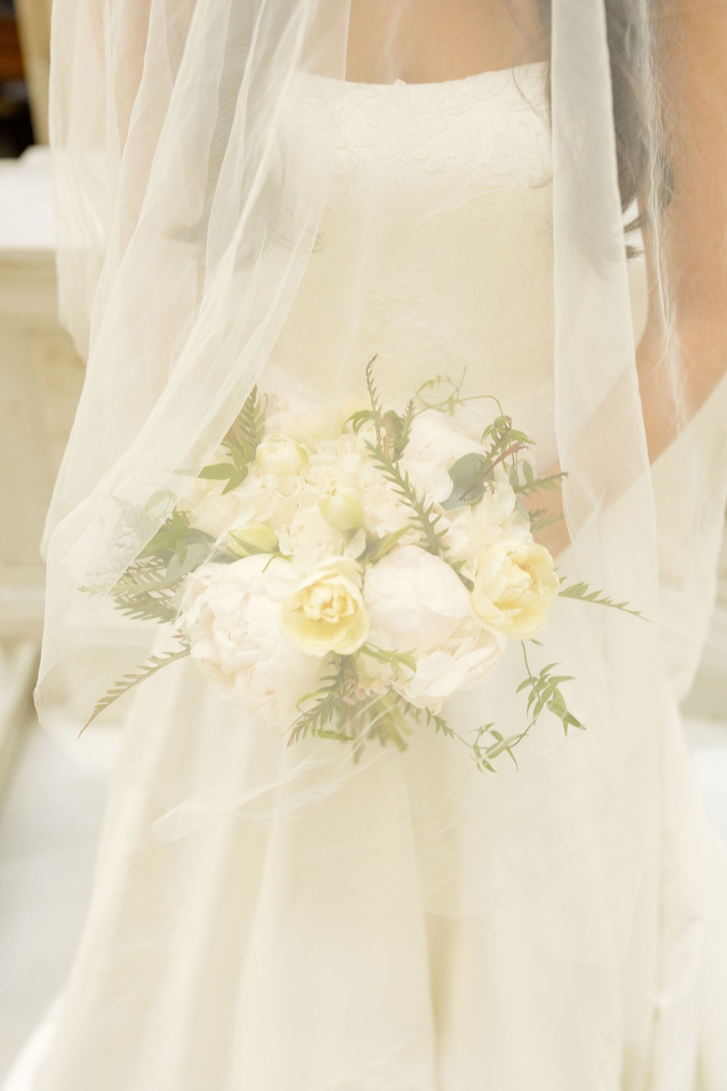 Delicate white floral arrangement with roses and greenery adorning sheer fabric.
