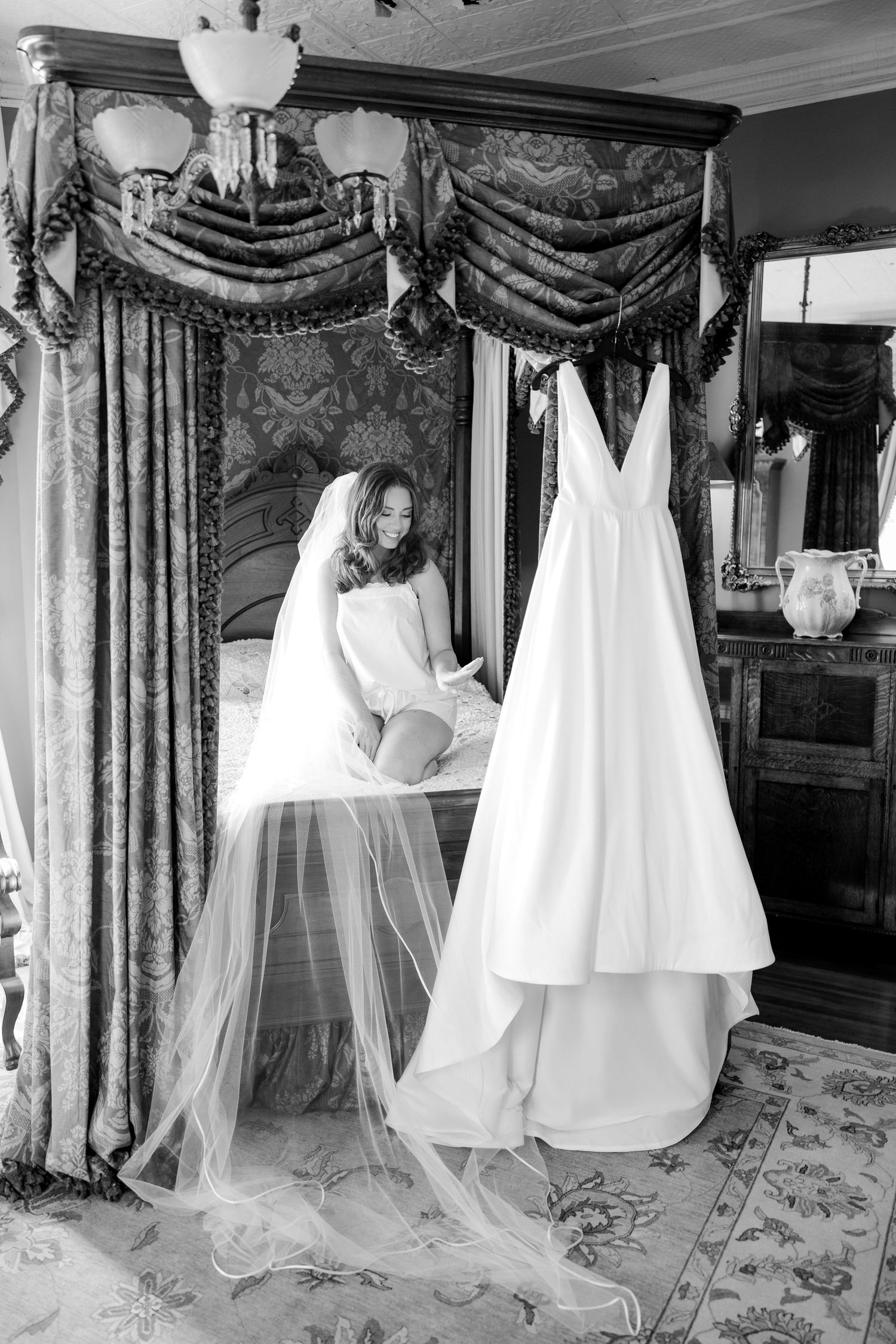 A collection of elegant white wedding dresses displayed on hangers against ornate curtains in a bridal boutique.