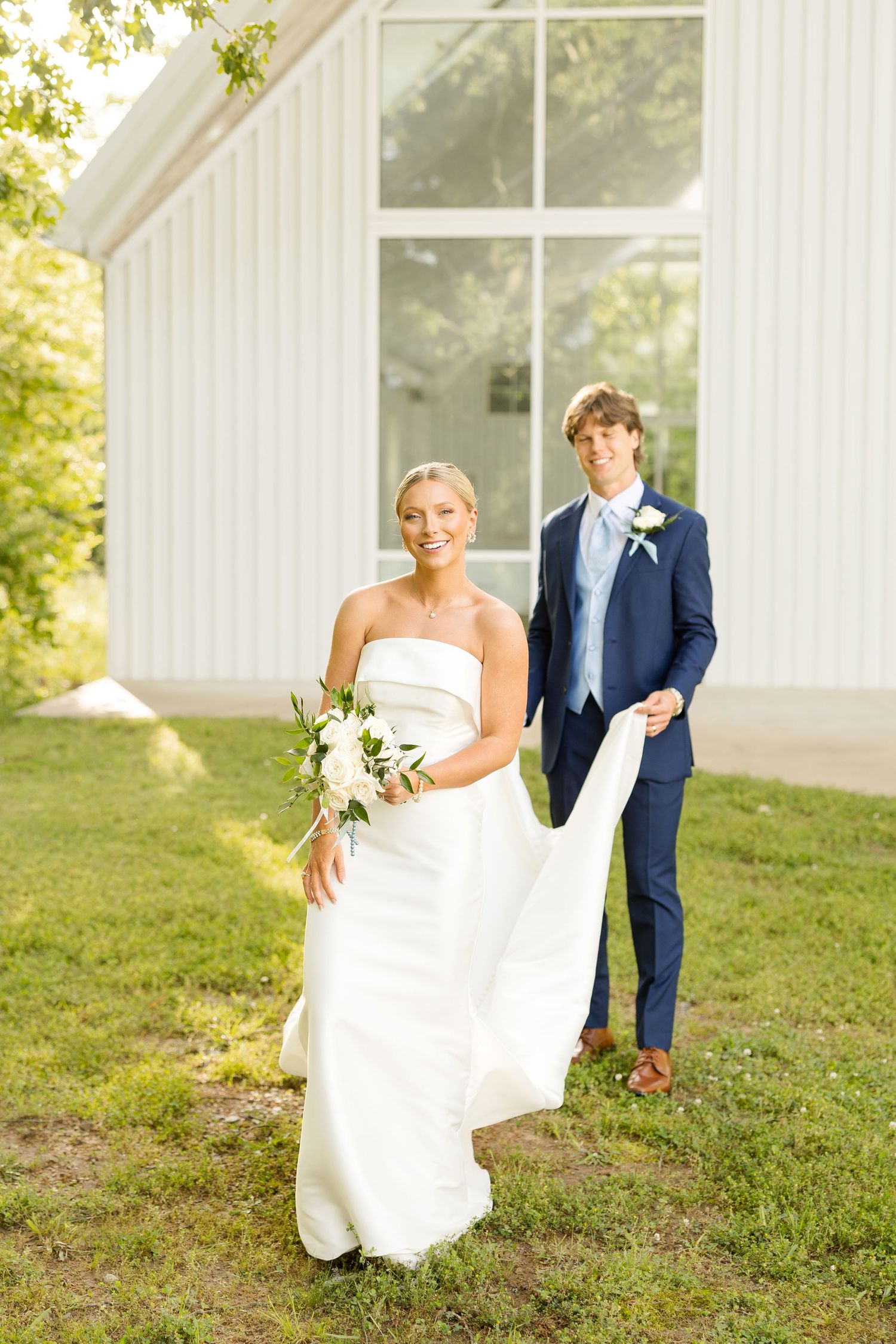 Wedding couple taking candid photos outside white chapel on grassy hillside.Cold Springs Events