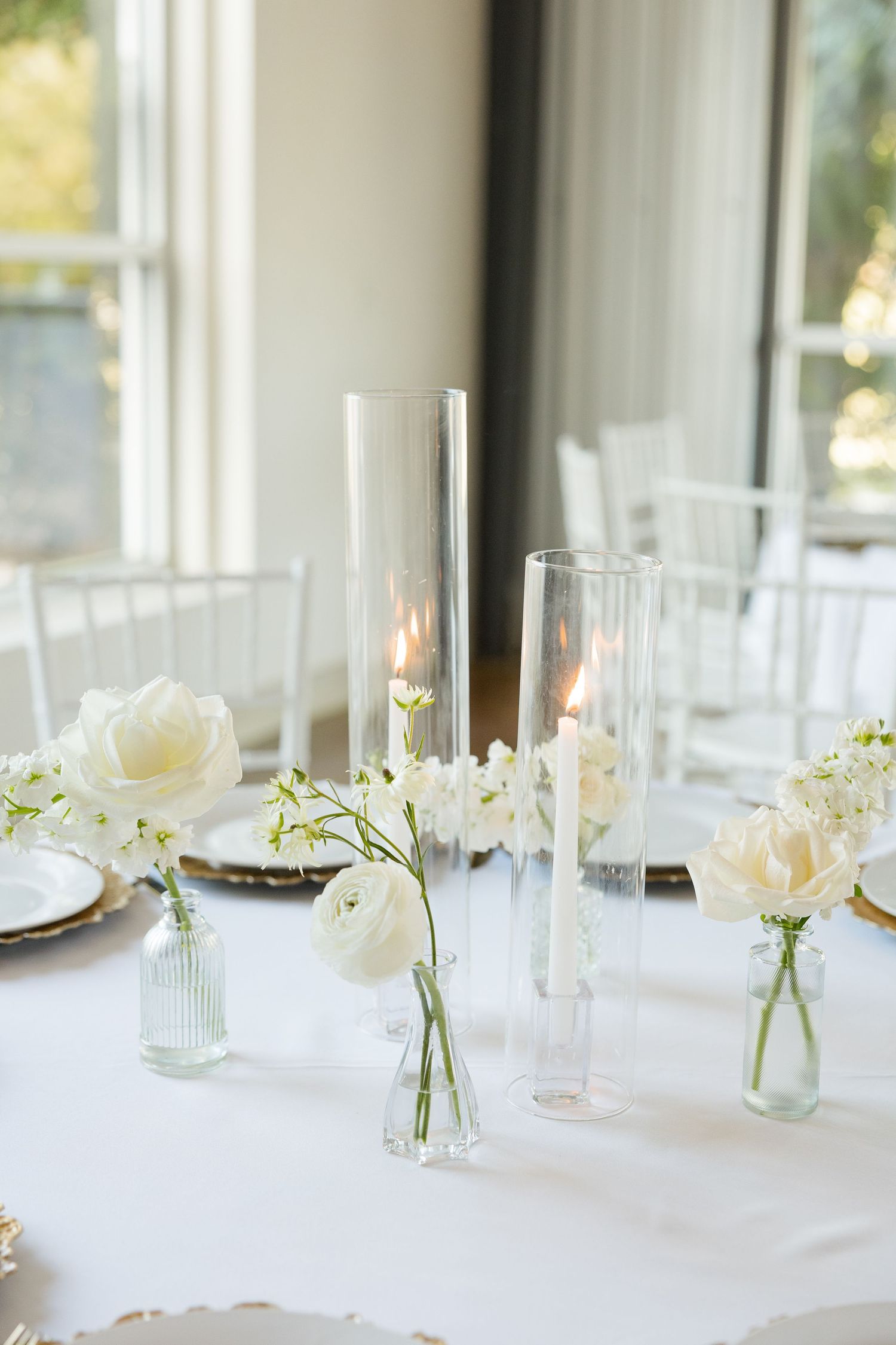 Minimalist table settings with delicate bud vases and glassware in bright reception space. Cold Springs