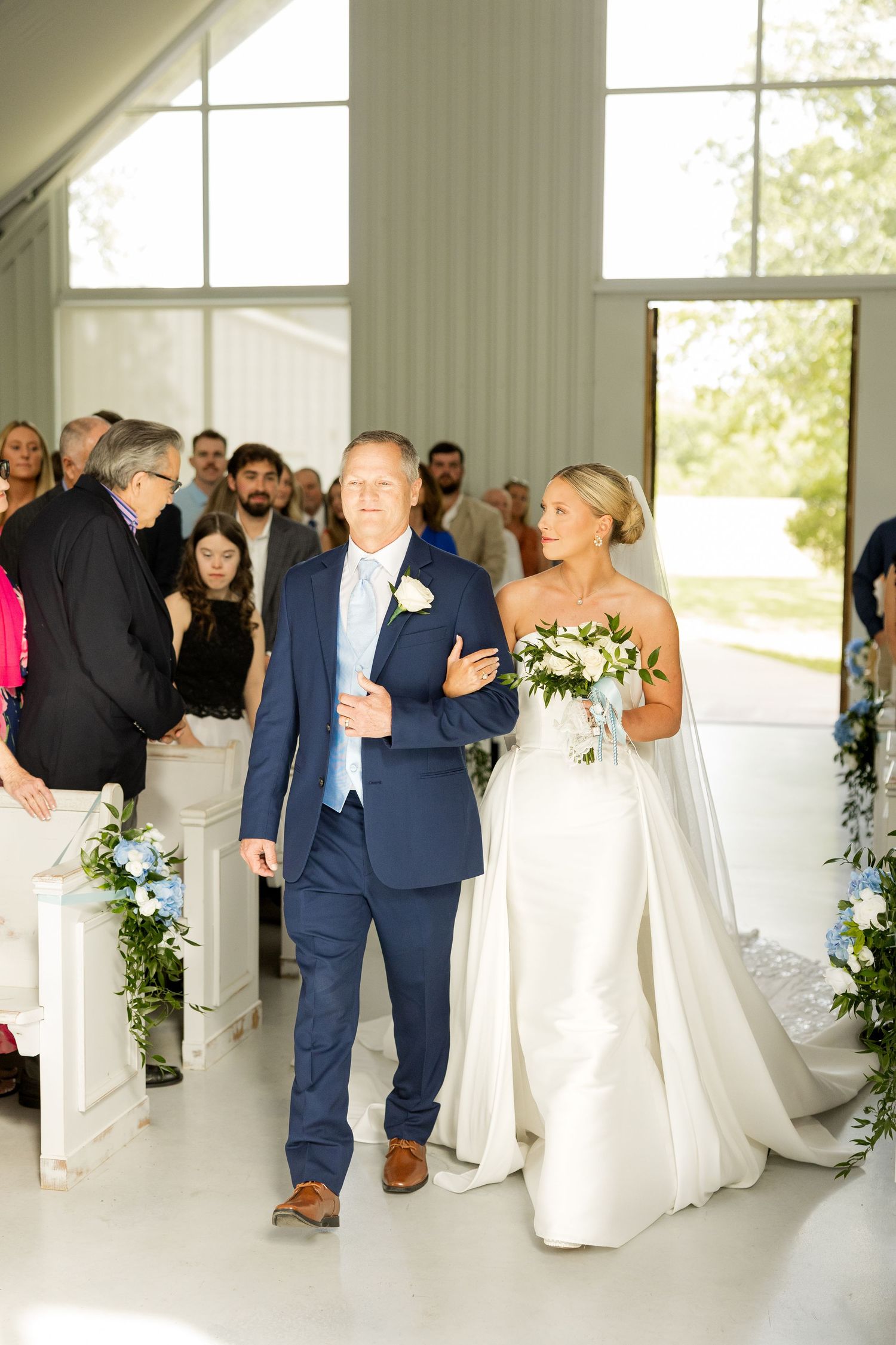 Wedding party celebrates in a bright white chapel with joyful candid moments. Cold Springs Events