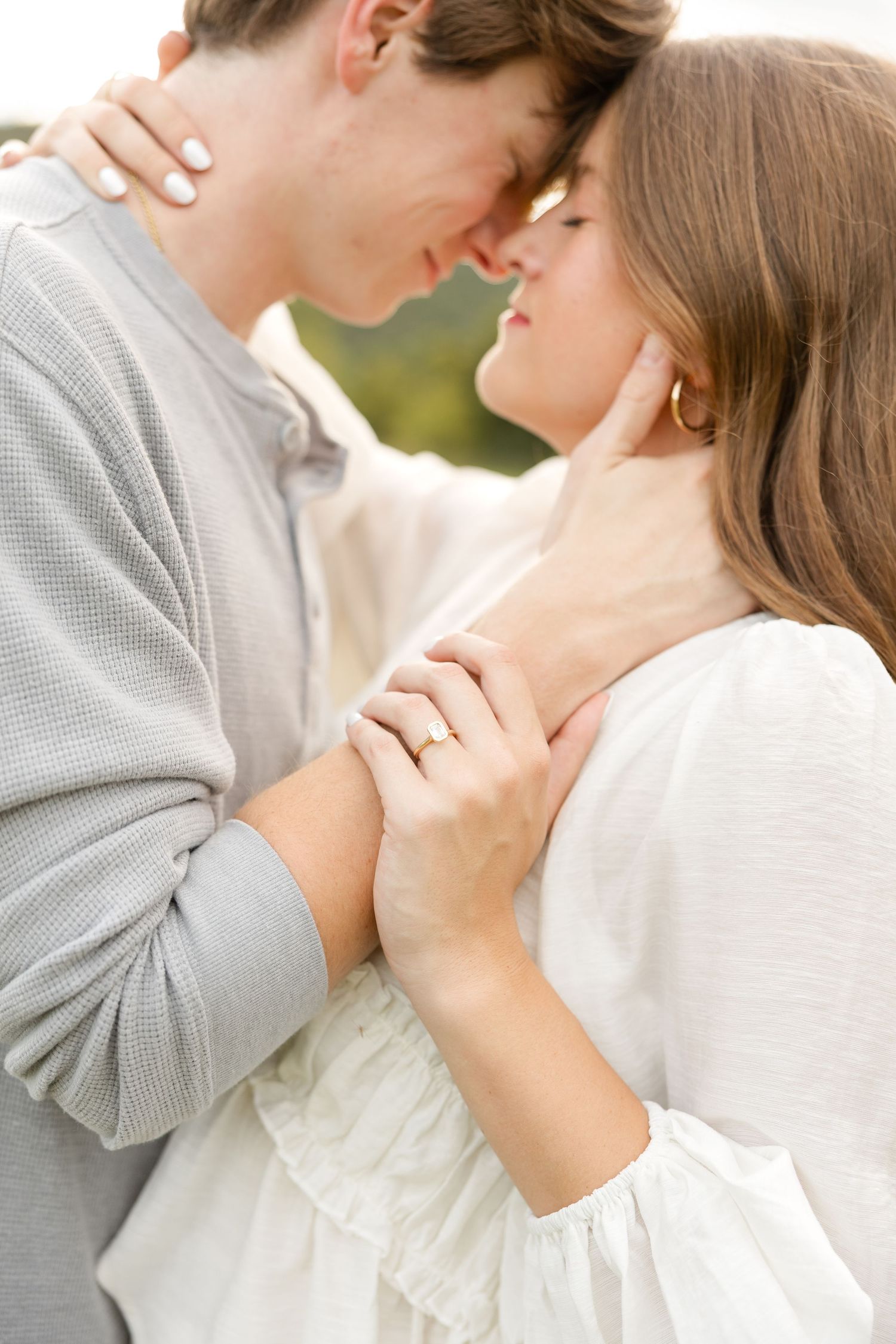 An intimate moment between a couple showing an engagement ring in natural lighting.