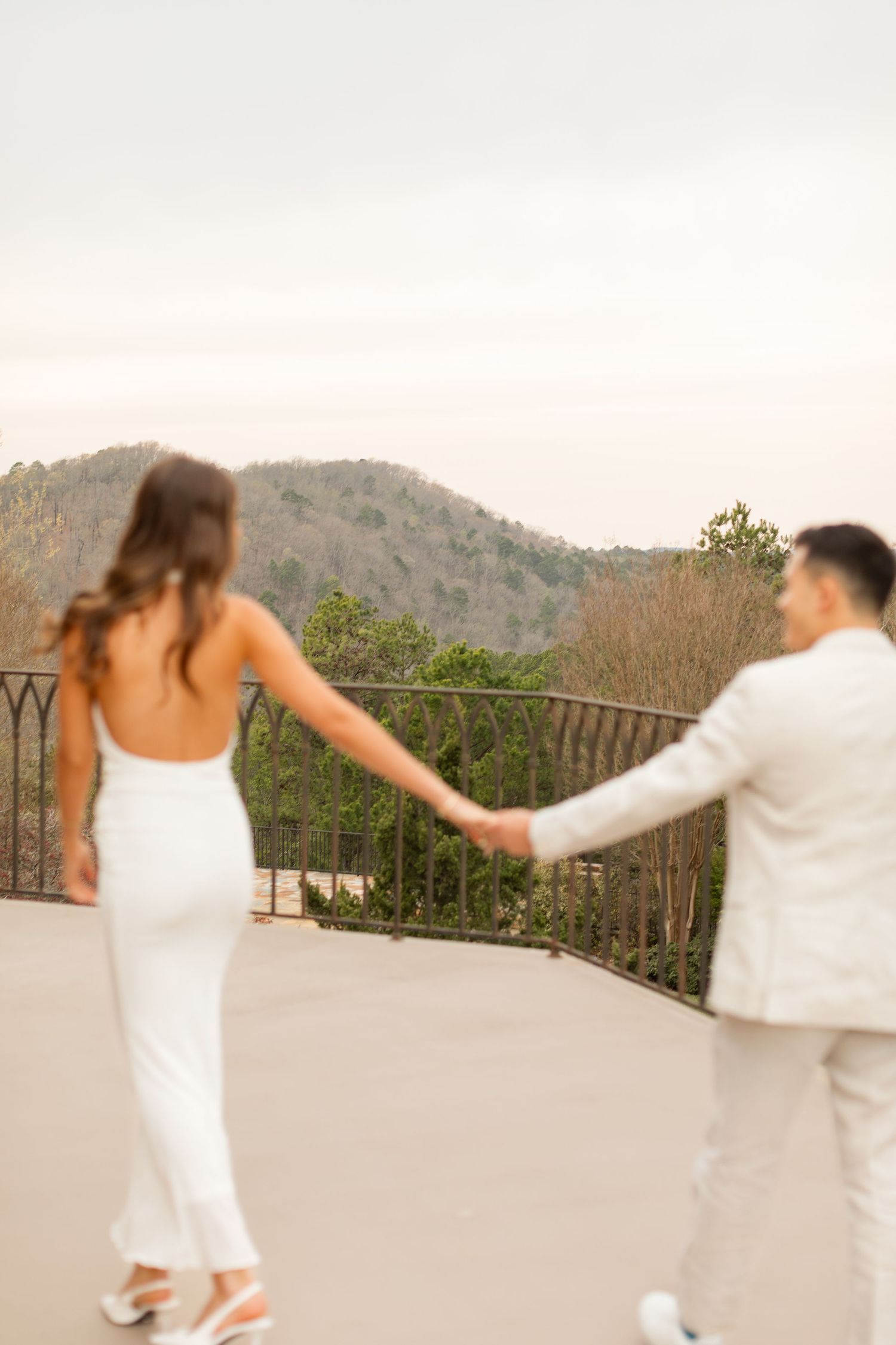 A couple in white attire dances on an outdoor terrace with mountain views in the background. Goodwin Manor.