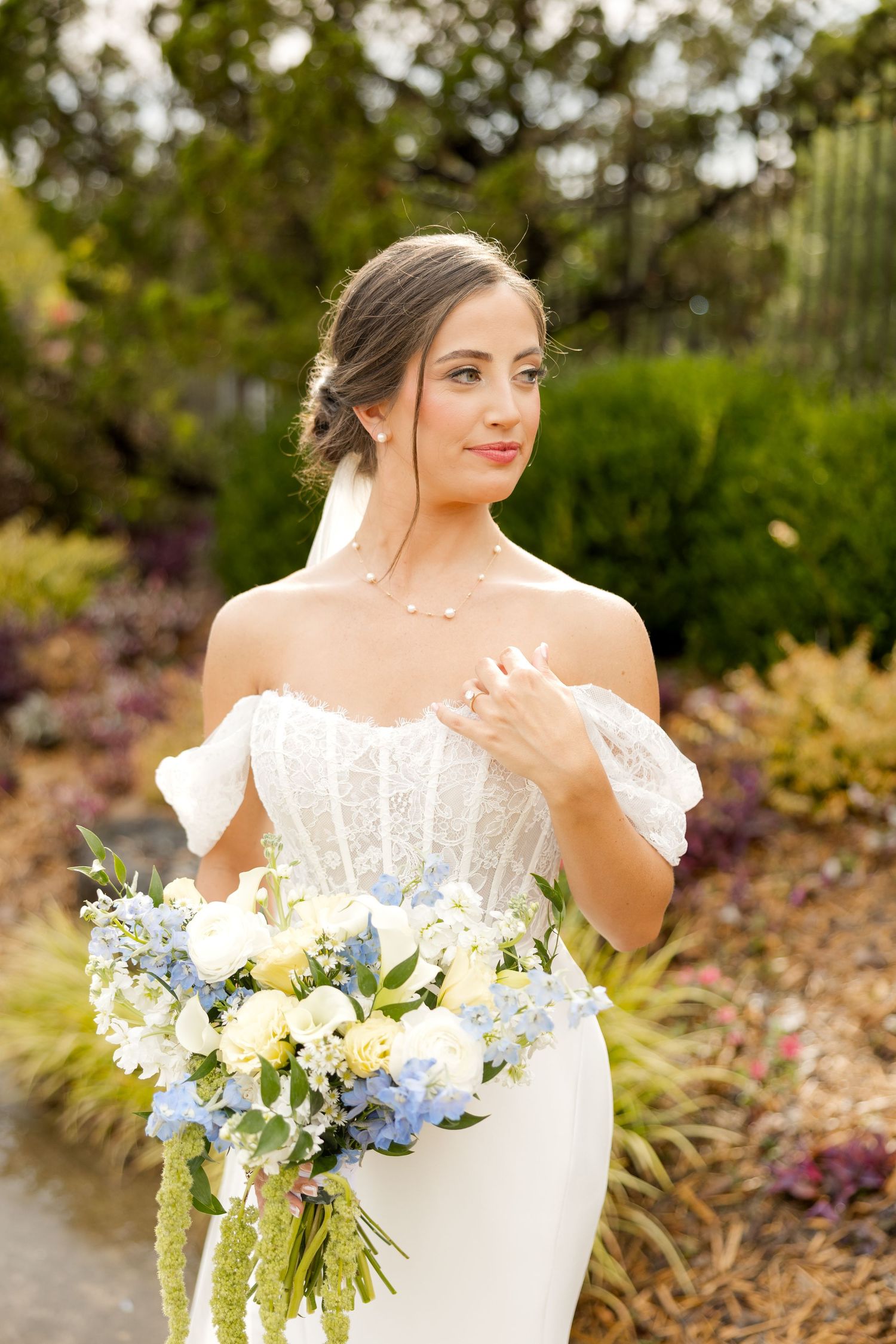 A white bridal bouquet with blue and yellow flowers against a natural garden backdrop.Botanical Gardens of the Ozarks