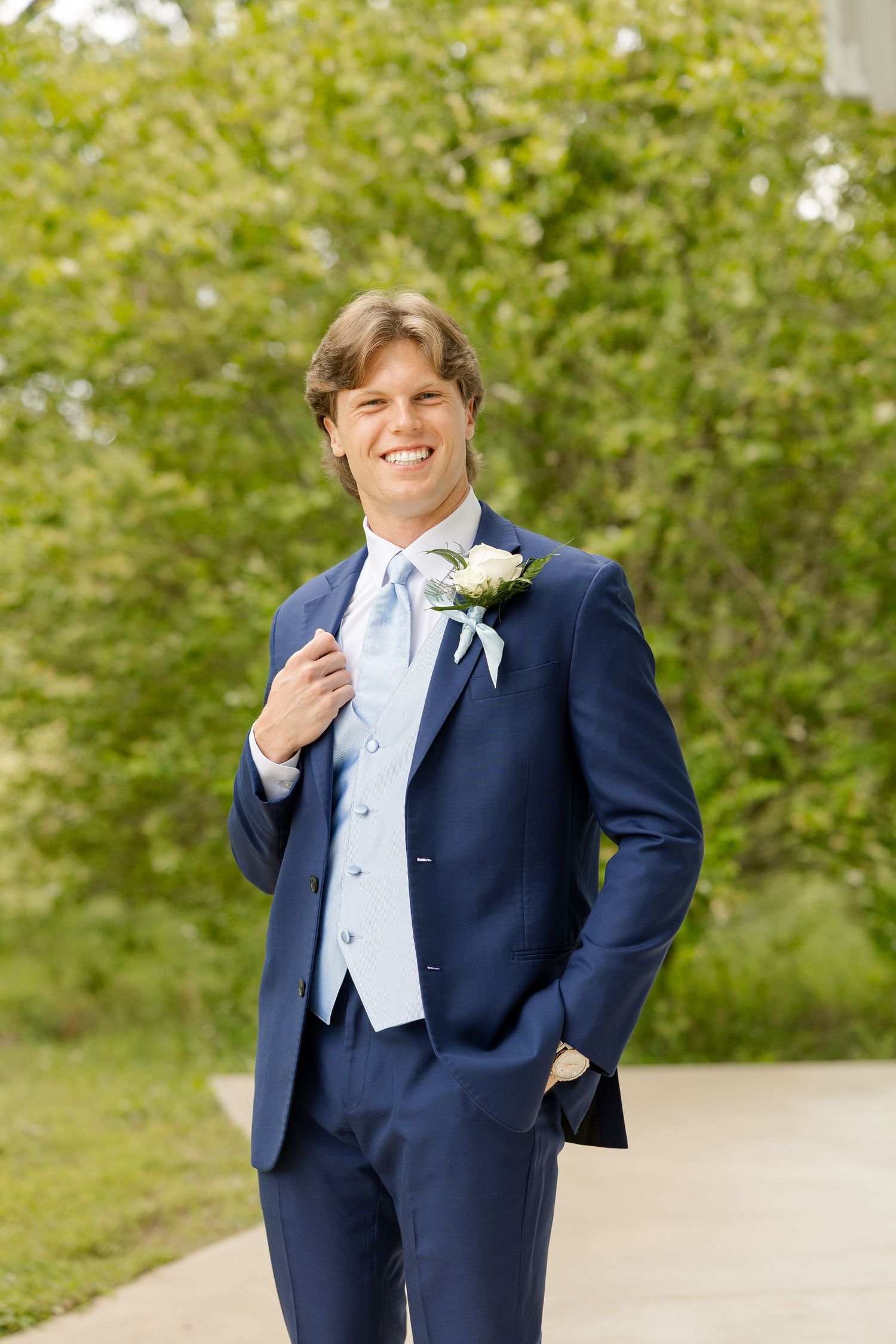 A groom in a navy suit and white bowtie smiles outdoors on his wedding day. Cold Springs Events