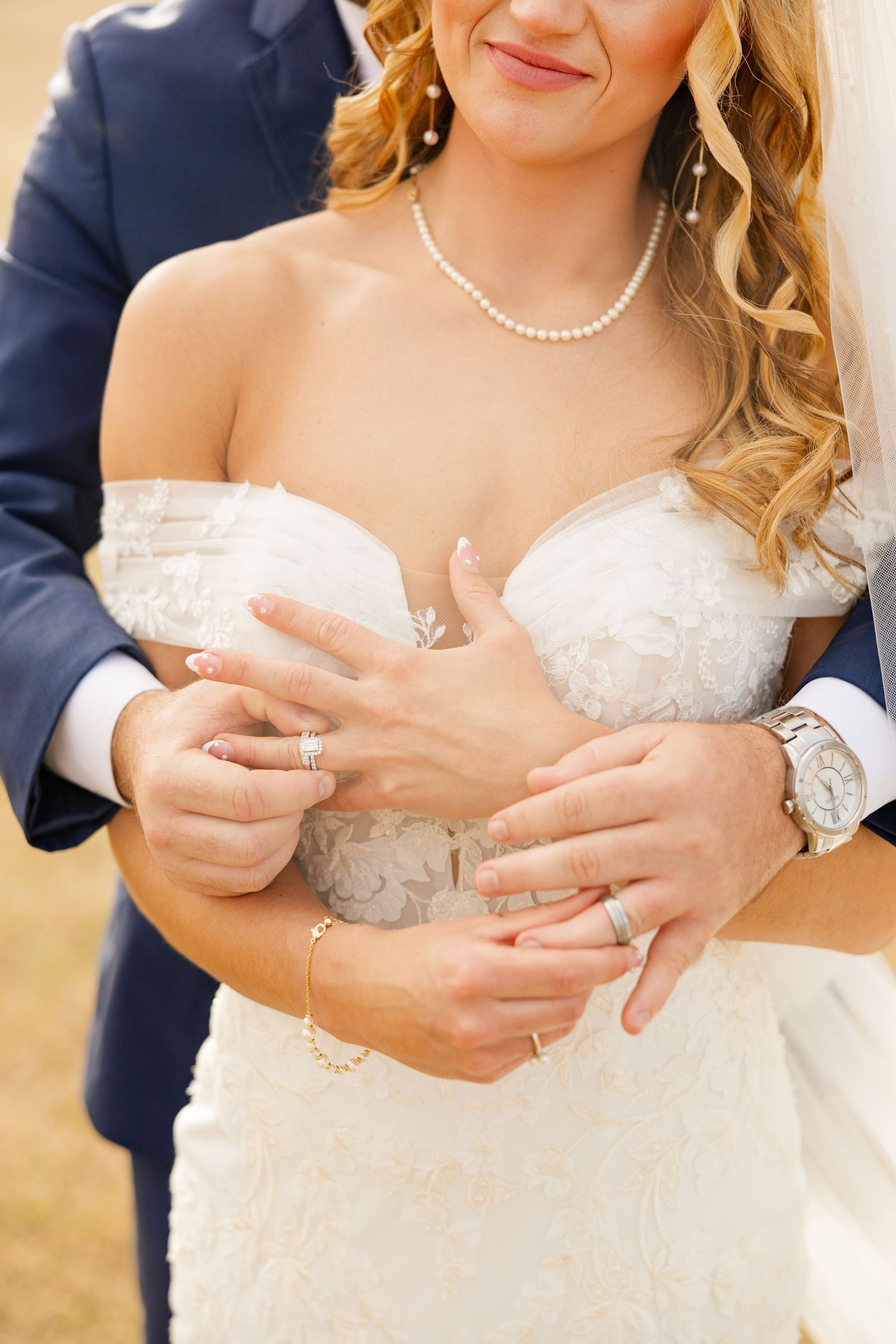 Close-up of wedding rings and lace details on a bride's dress.