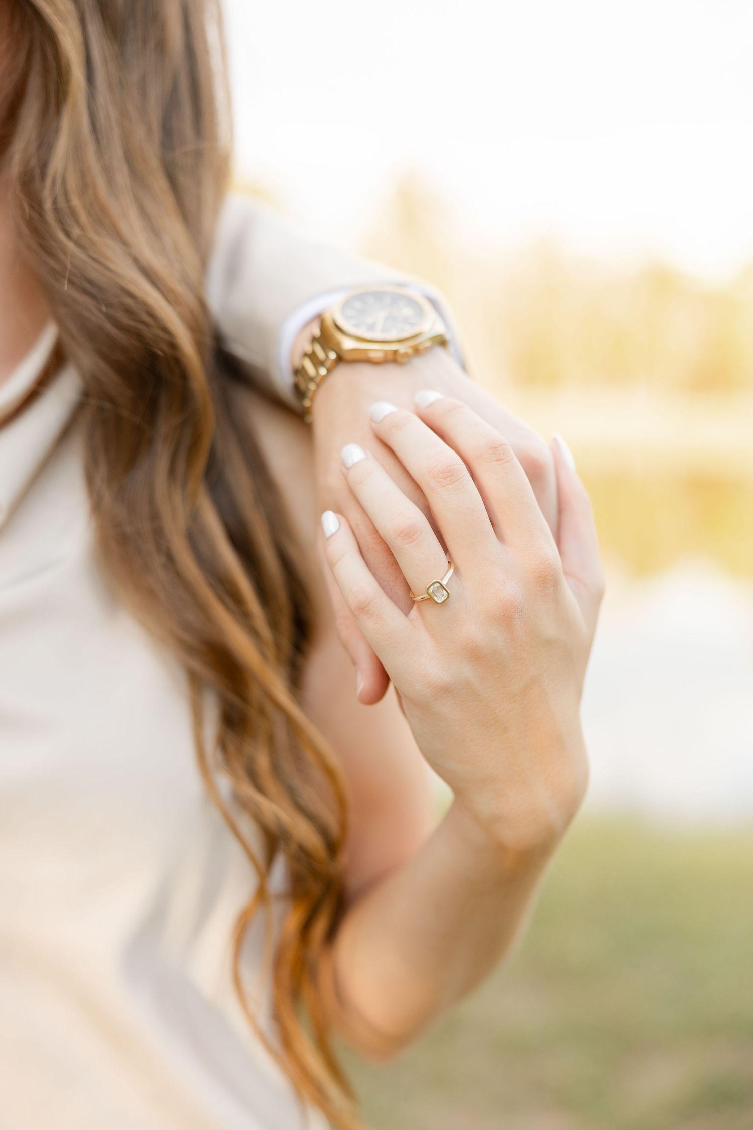 Close-up shots of hands displaying an engagement ring with sunlit bokeh in the background.