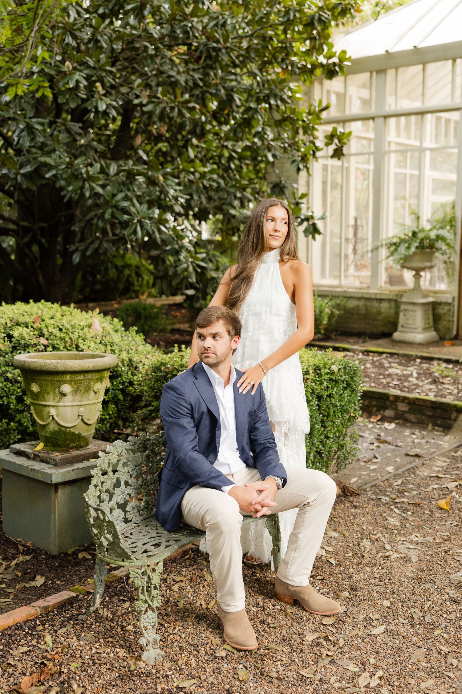 Casual engagement photos taken in a garden with stone pathways and lush greenery.