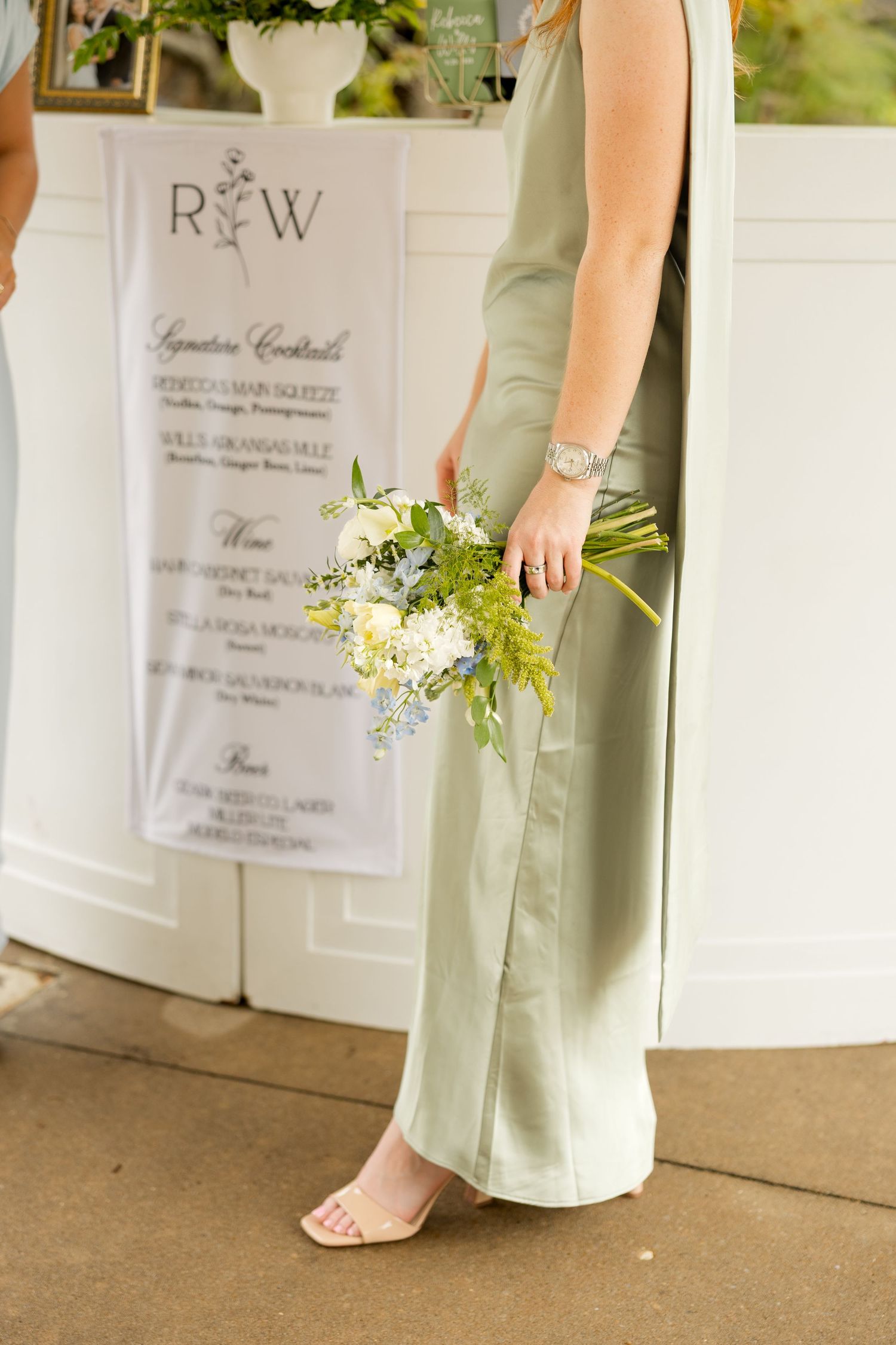 Wedding signage and floral details against a white wall backdrop. Botanical Gardens of the Ozarks