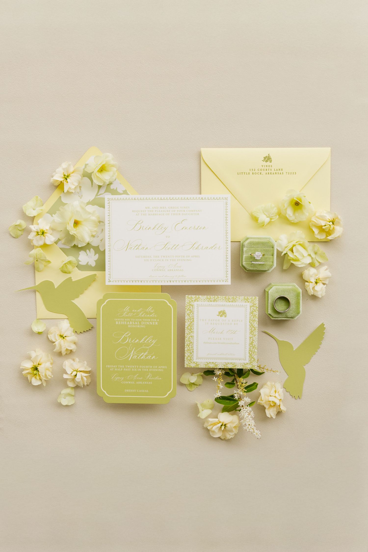 Elegant yellow and green wedding invitation suite with floral accents, ring box, and hummingbird cutouts on a neutral background.