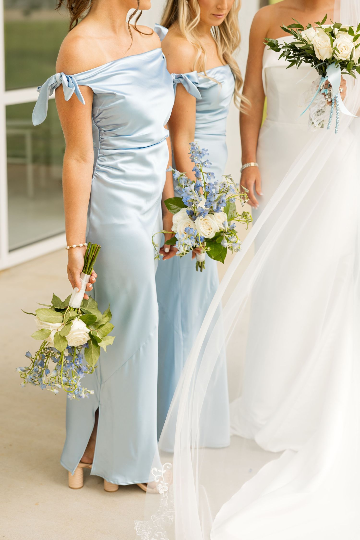 Bridesmaids in light blue dresses hold white and blue floral bouquets at an elegant wedding ceremony. Cold Springs Events.